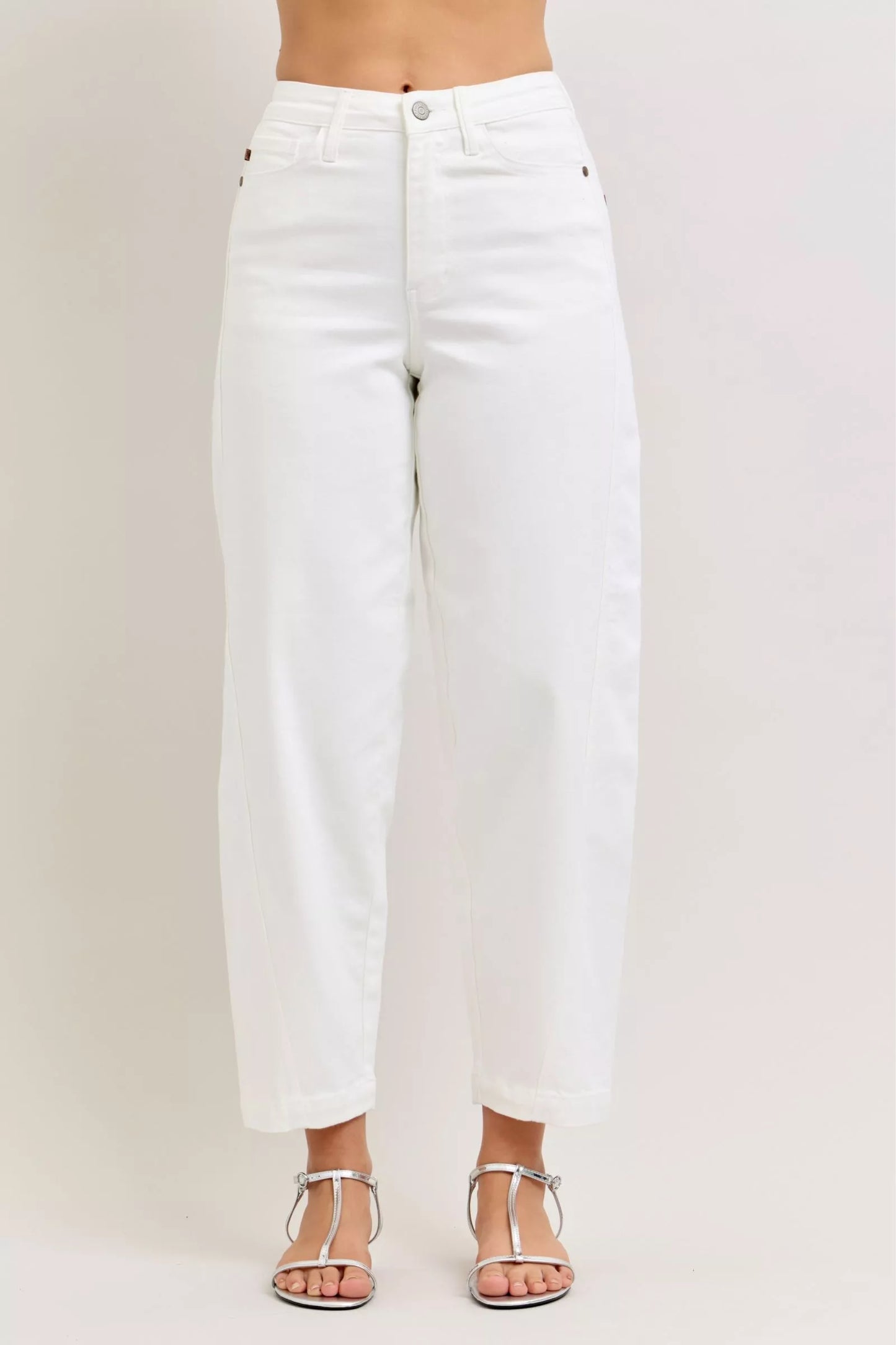 Woman wearing white high rise barrel leg jeans with tapered ankle and silver sandals