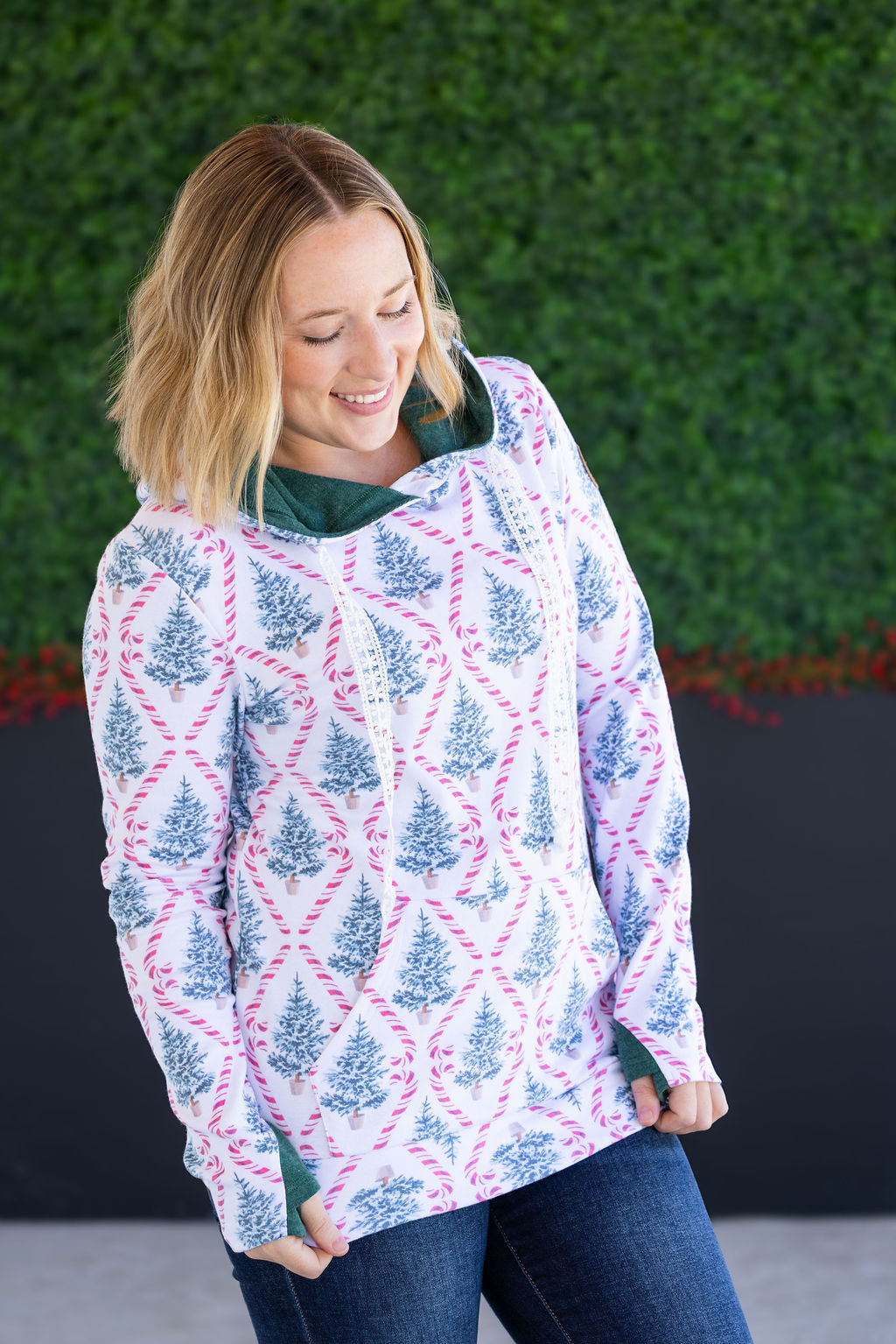 Woman wearing Candy Cane Lane print hoodie with pockets and jeans
