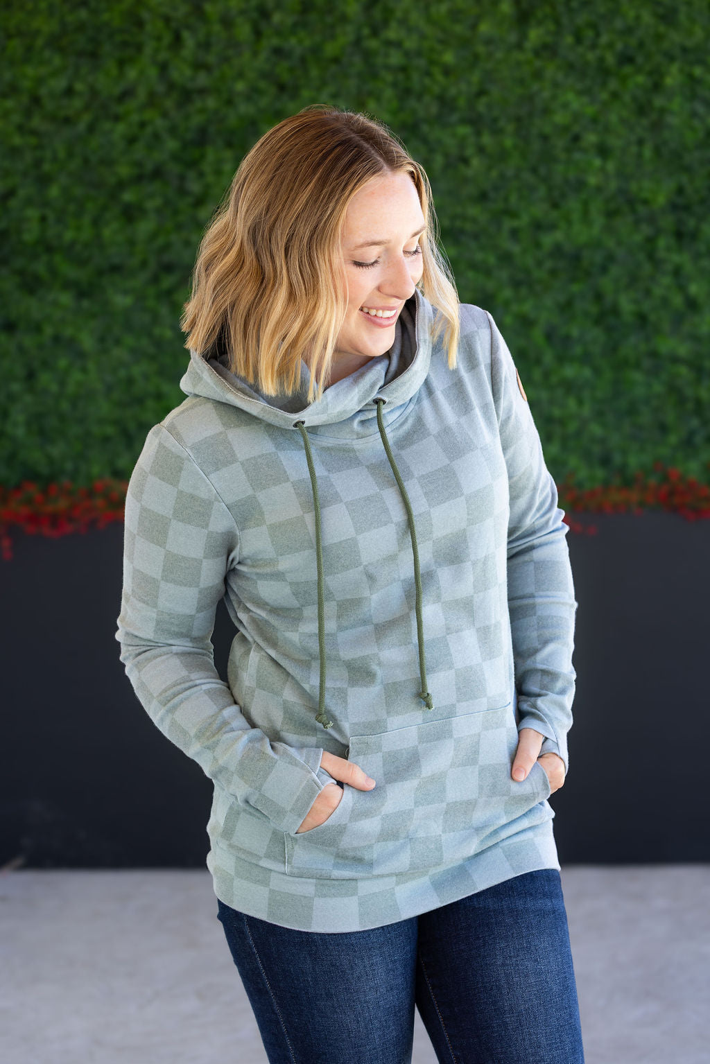 Woman wearing olive checkers hoodie with pockets and jeans