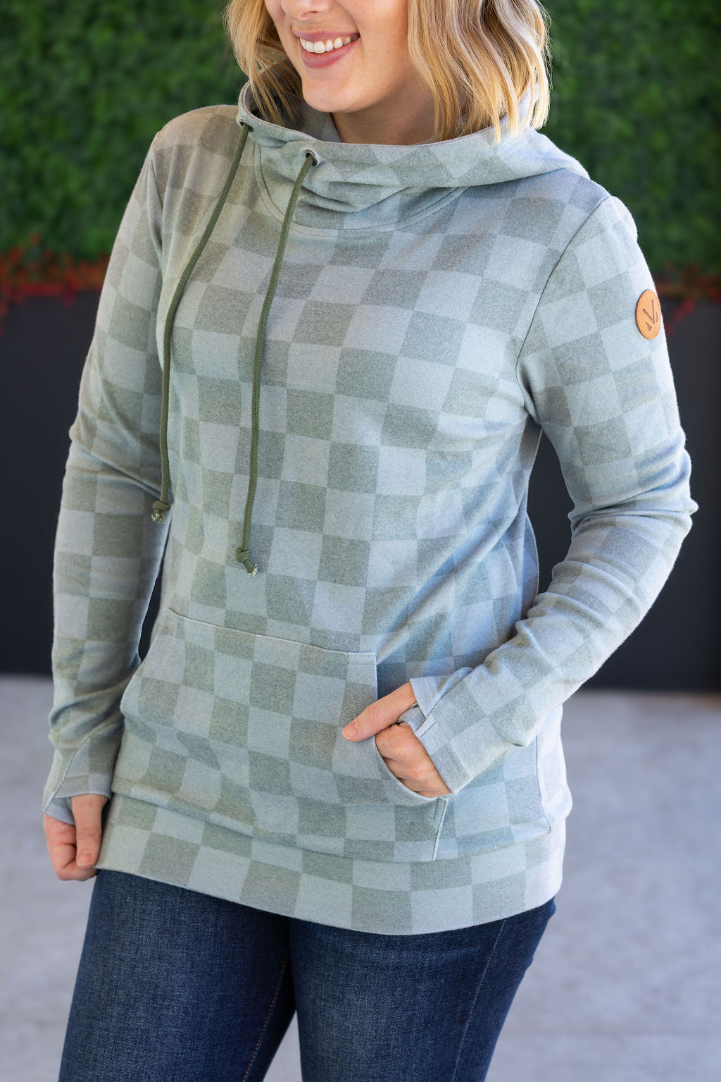 Woman wearing olive checkers hoodie with pockets and jeans