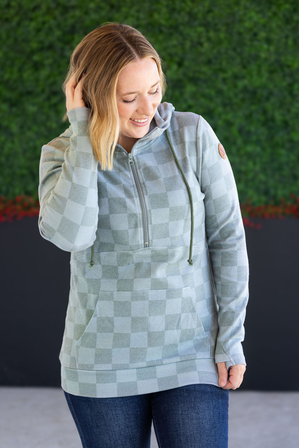 Woman wearing olive checkers half-zip hoodie with jeans