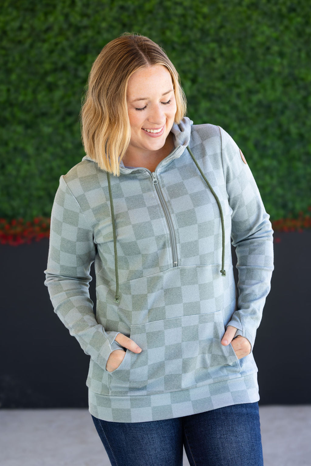 Woman wearing olive checkers half-zip hoodie with jeans