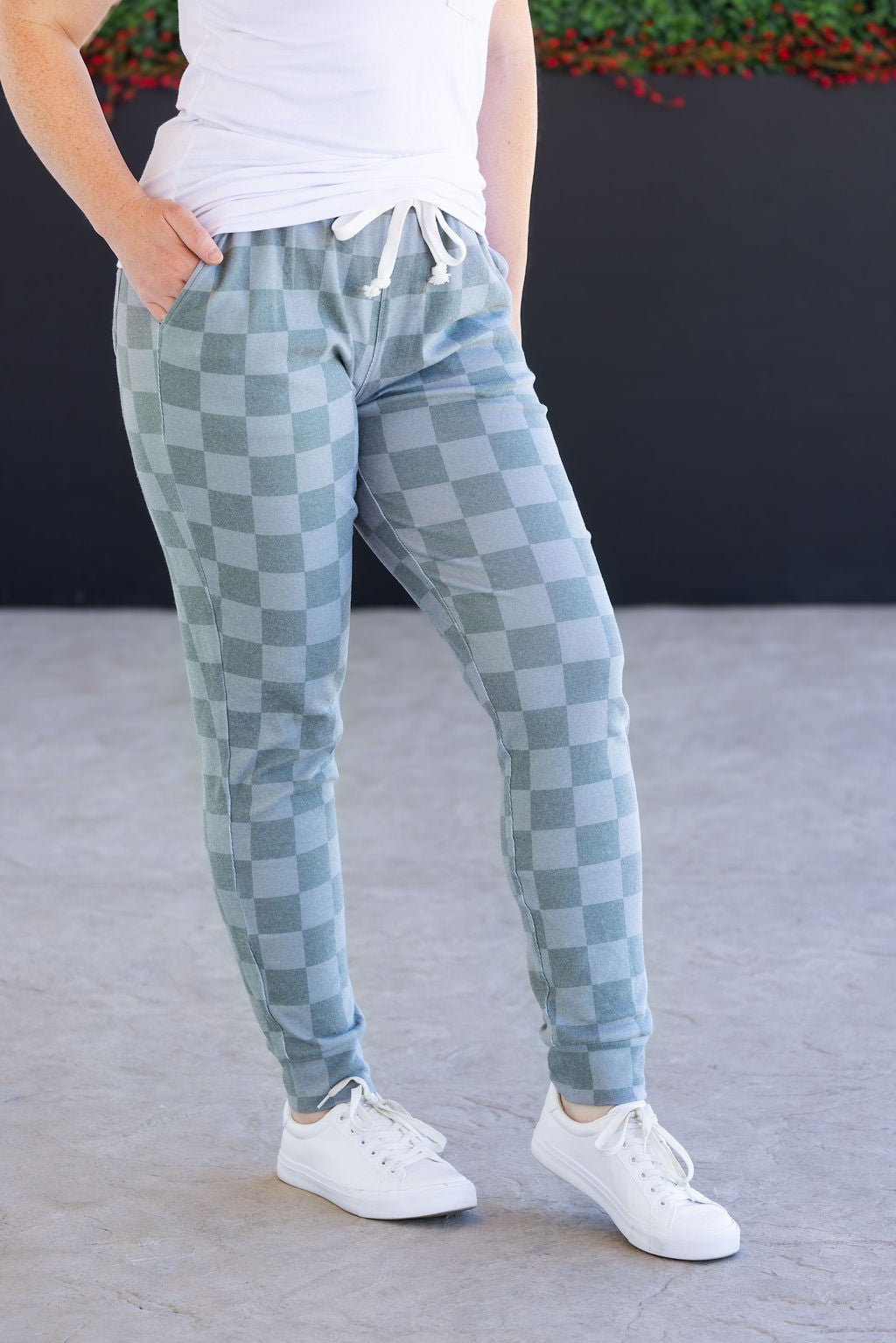Woman wearing olive checkers joggers with white top and sneakers