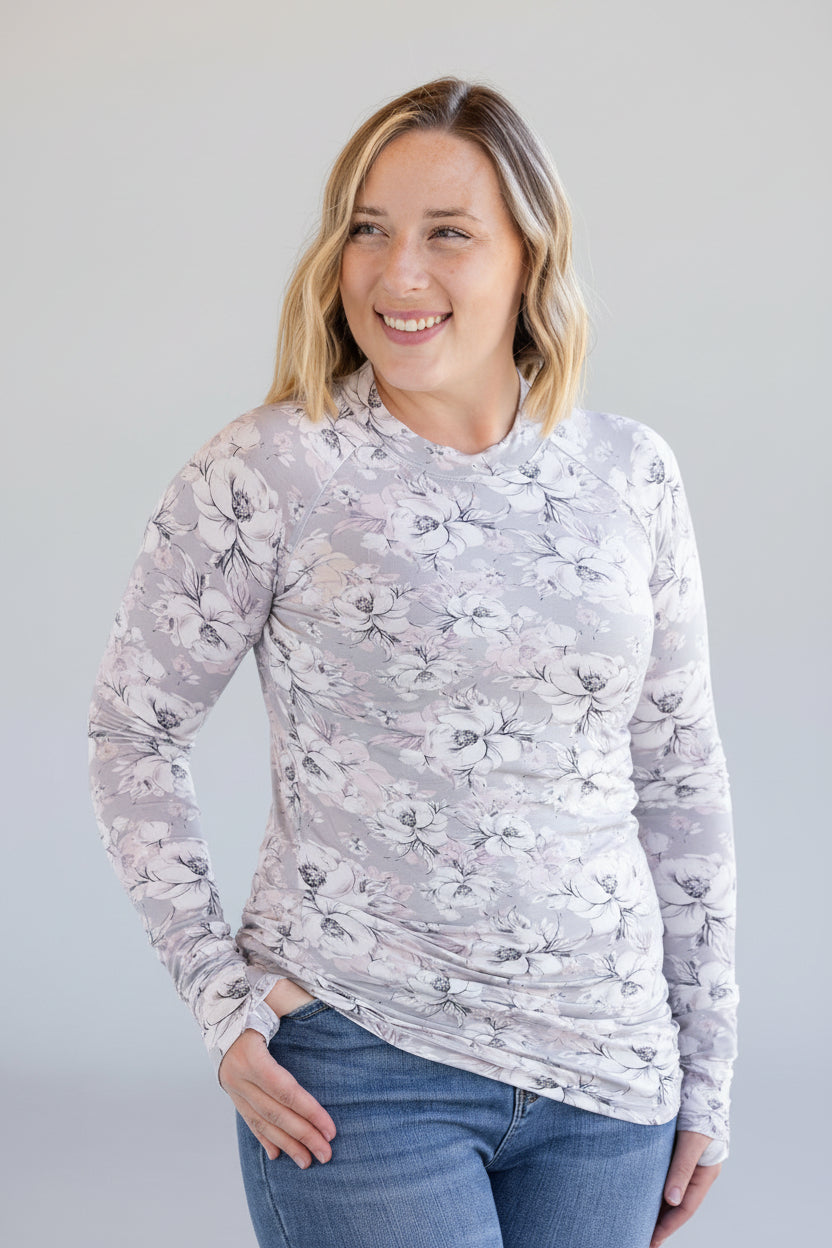 Woman wearing gray fitted long sleeve top with vintage floral print and high neckline