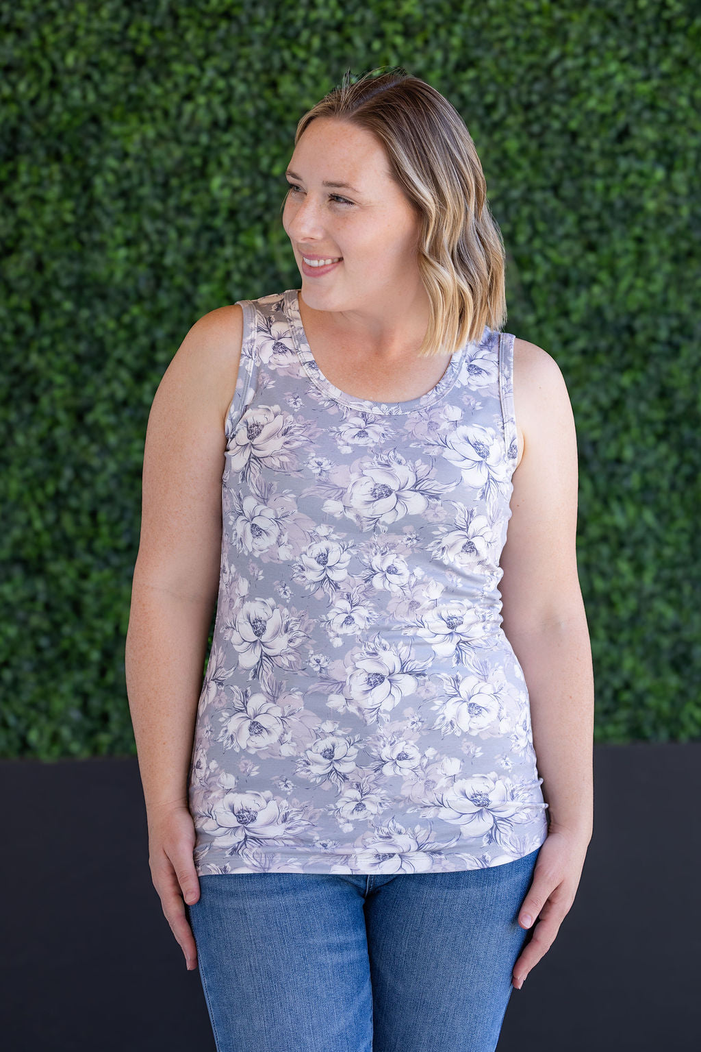 Woman wearing gray ribbed tank top with white floral print, scoop neckline, and fitted silhouette