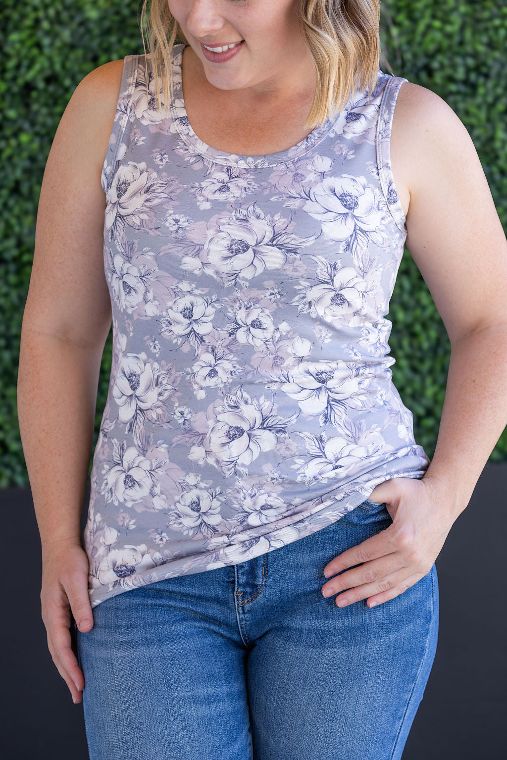 Woman wearing gray ribbed tank top with white floral print, scoop neckline, and fitted silhouette