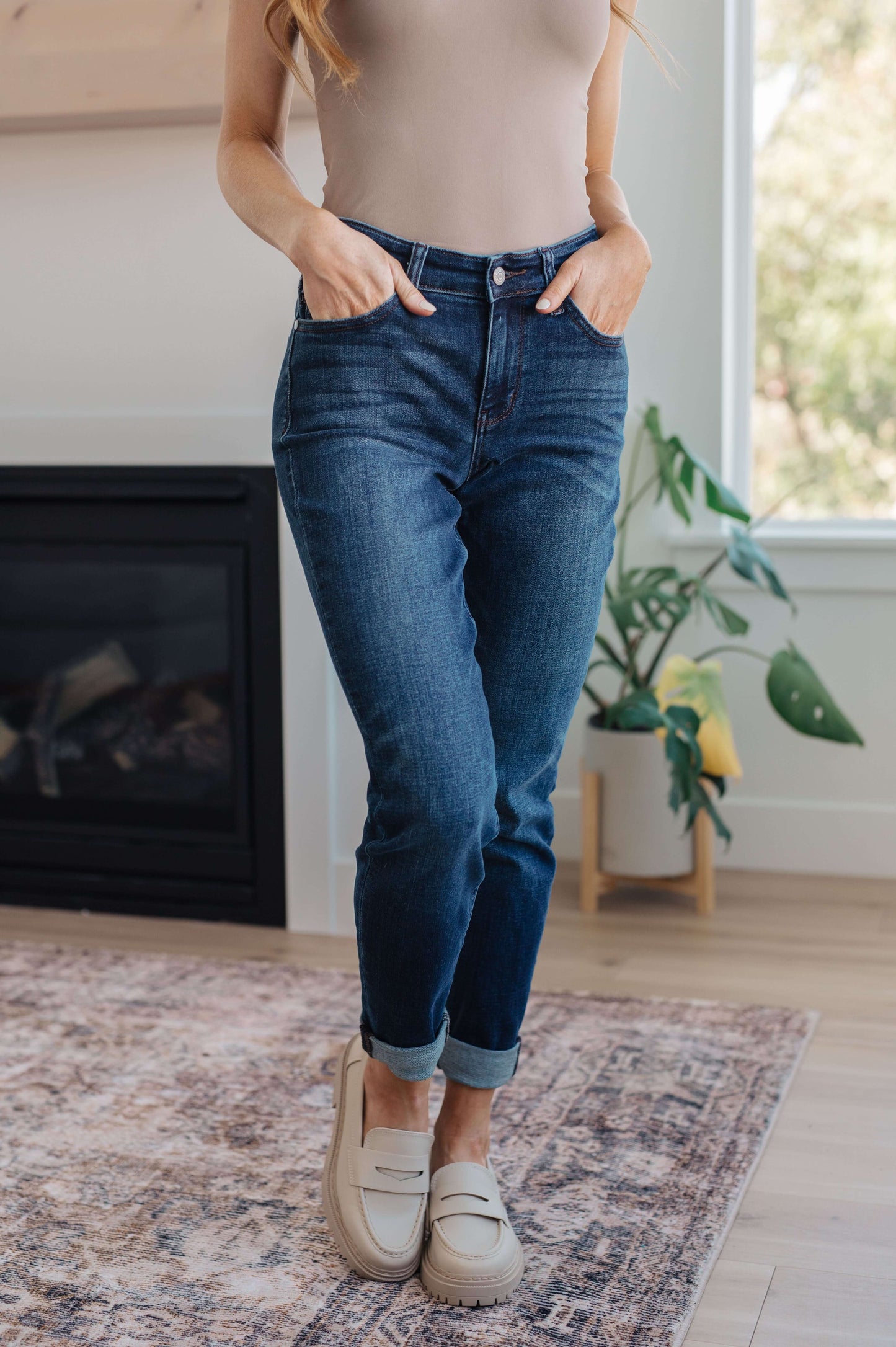 Model wearing dark wash slim fit jeans with cuffed hem and loafers