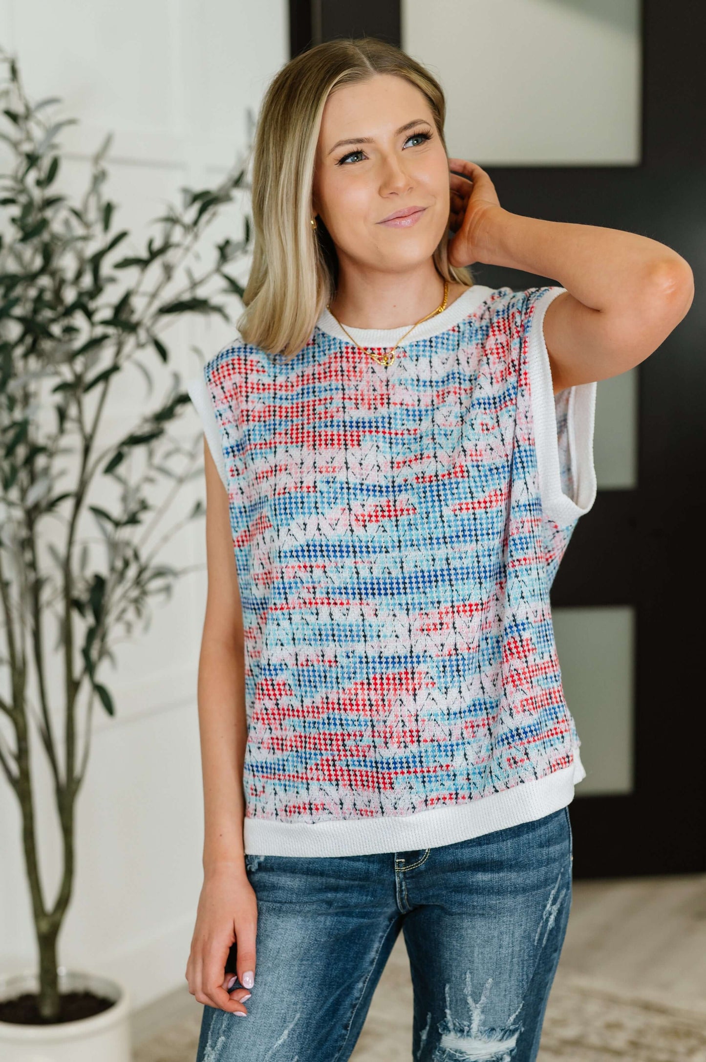 Model wearing red, blue, and white textured knit top with ribbed trim and jeans