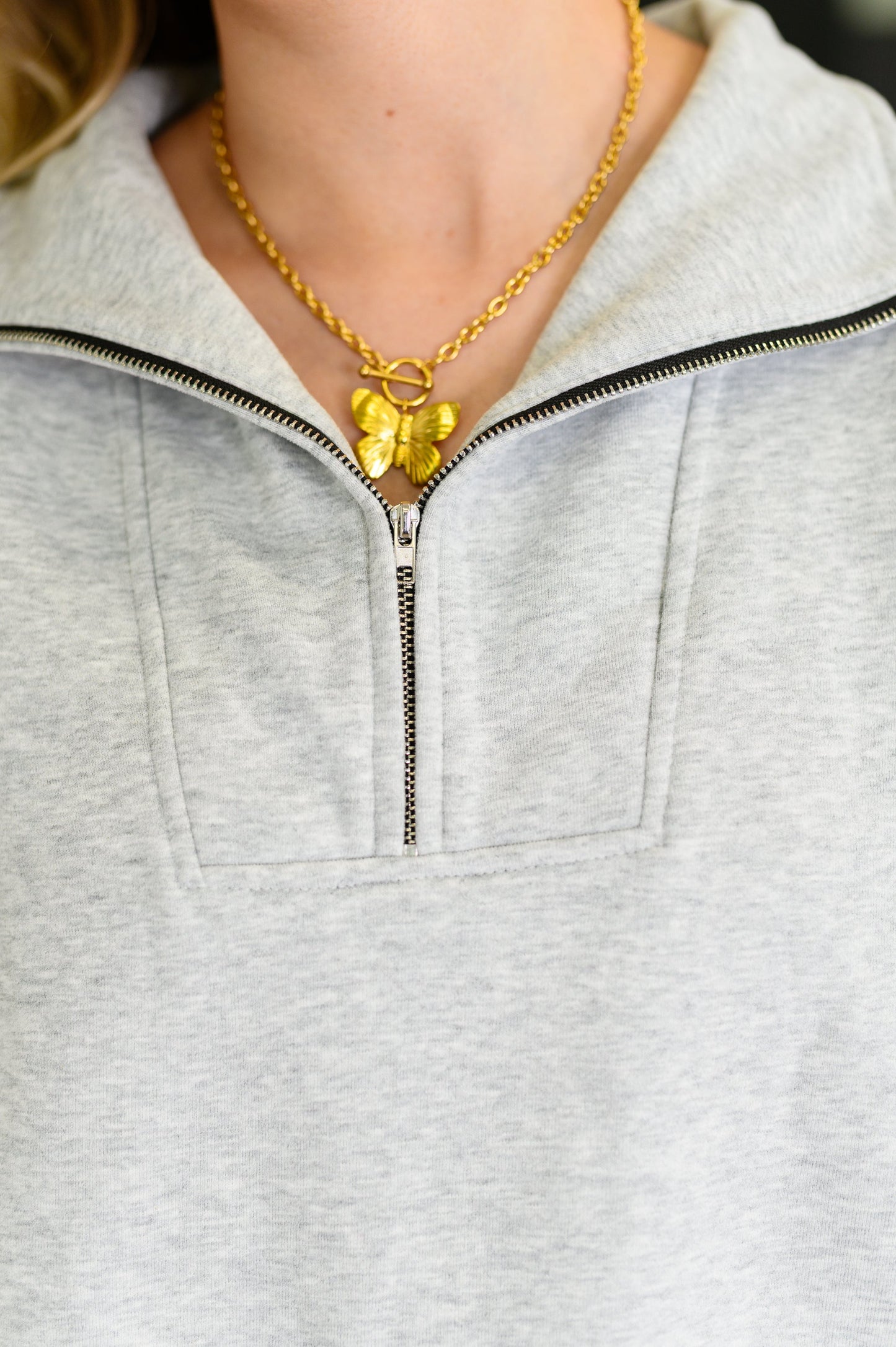 Woman wearing the Bonbon Delight Half Zip Pullover in grey fleece with half-zip neckline and kangaroo pocket.