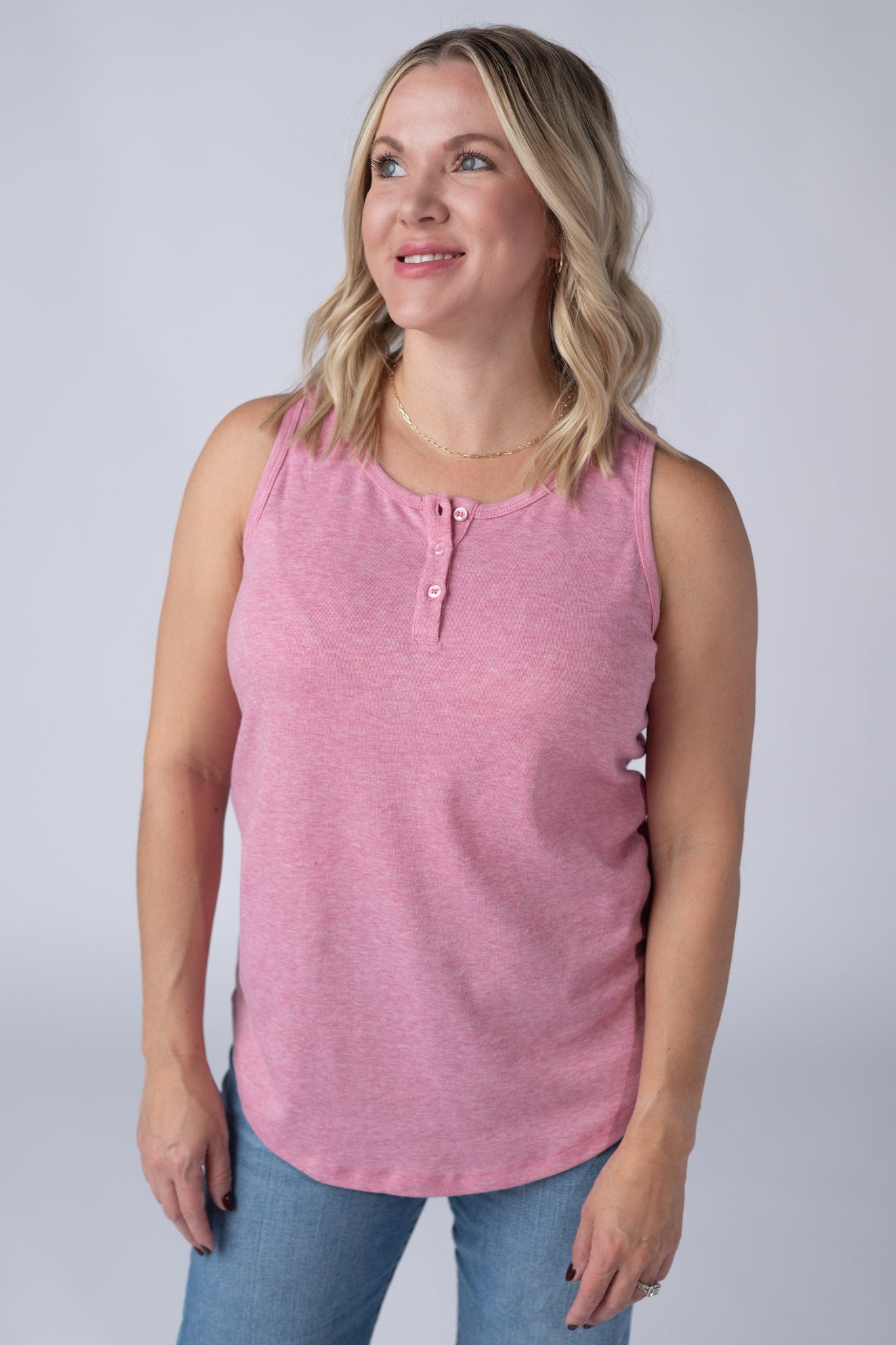 Woman wearing a heathered rose Alison Henley Tank with button detail neckline, paired with jeans