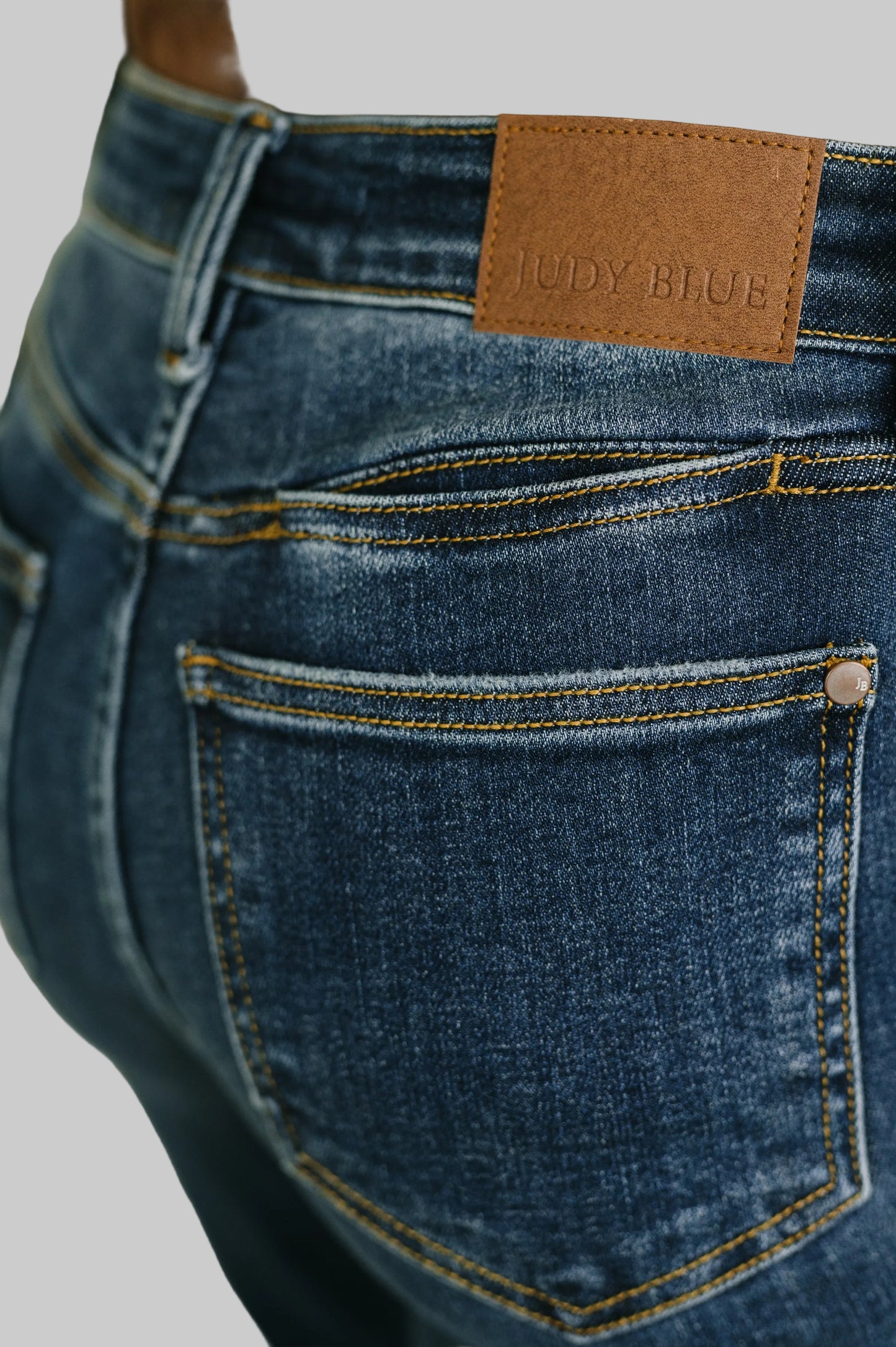 Casey Mid Rise Bootcut Jeans by Judy Blue in medium wash featuring front patch pockets and hem slit paired with brown top and black boots