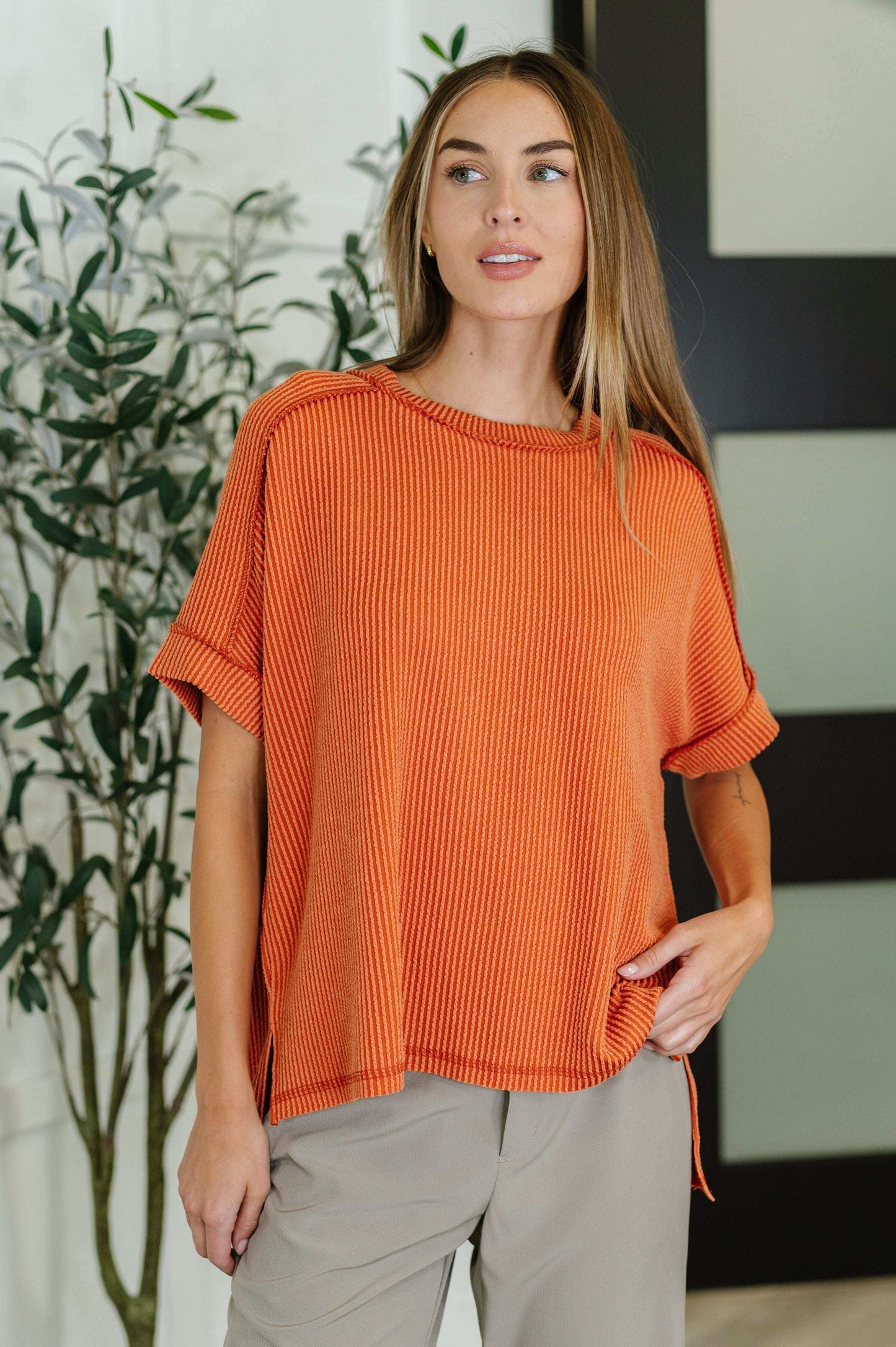 Woman wearing the Catch Me Loungin' Cable Ribbed Knit Top in burnt orange with raglan sleeves and side slits