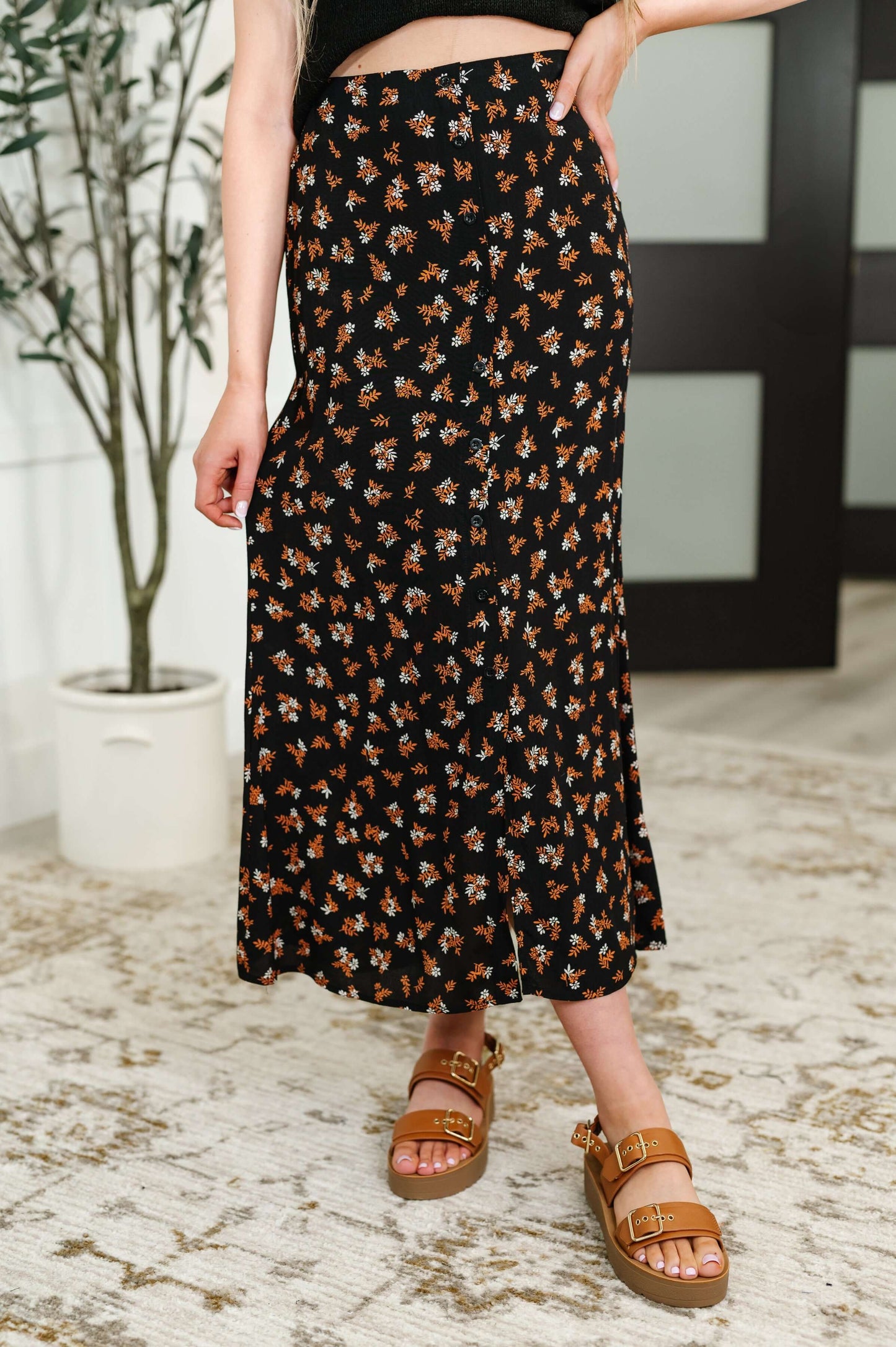 Model wearing floral button front midi skirt in rust, white, and black with platform sandals