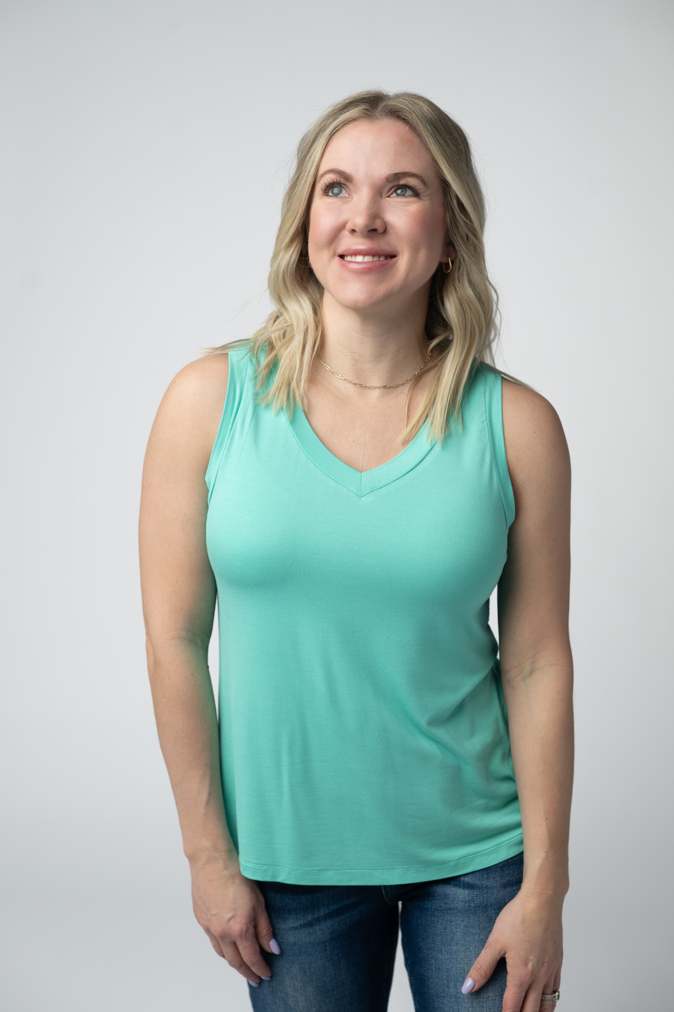 Woman wearing the Michelle Mae Noelle Tank in Turquoise, a lightweight v-neck sleeveless tank top in a bright aqua color