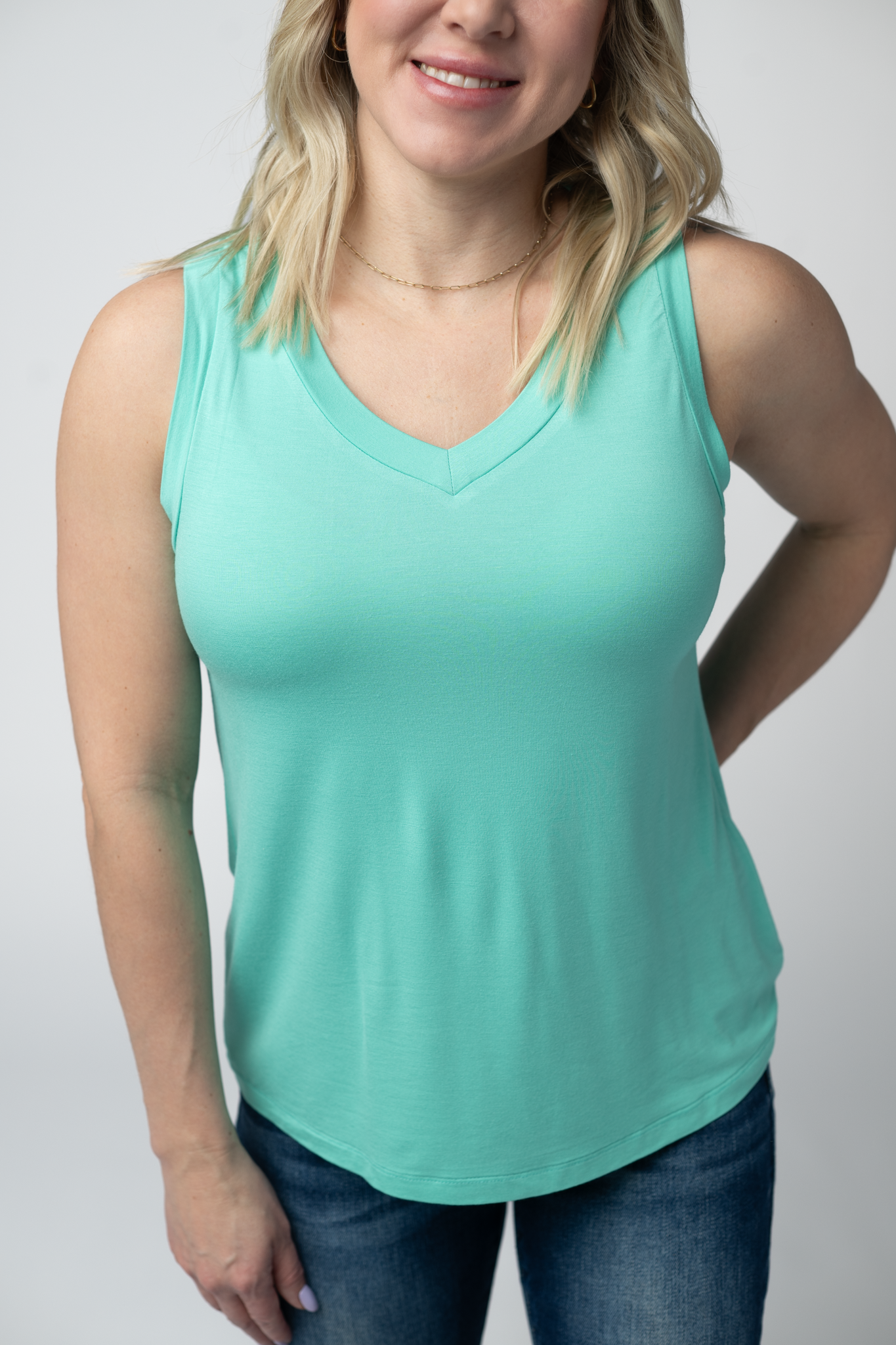 Woman wearing the Michelle Mae Noelle Tank in Turquoise, a lightweight v-neck sleeveless tank top in a bright aqua color