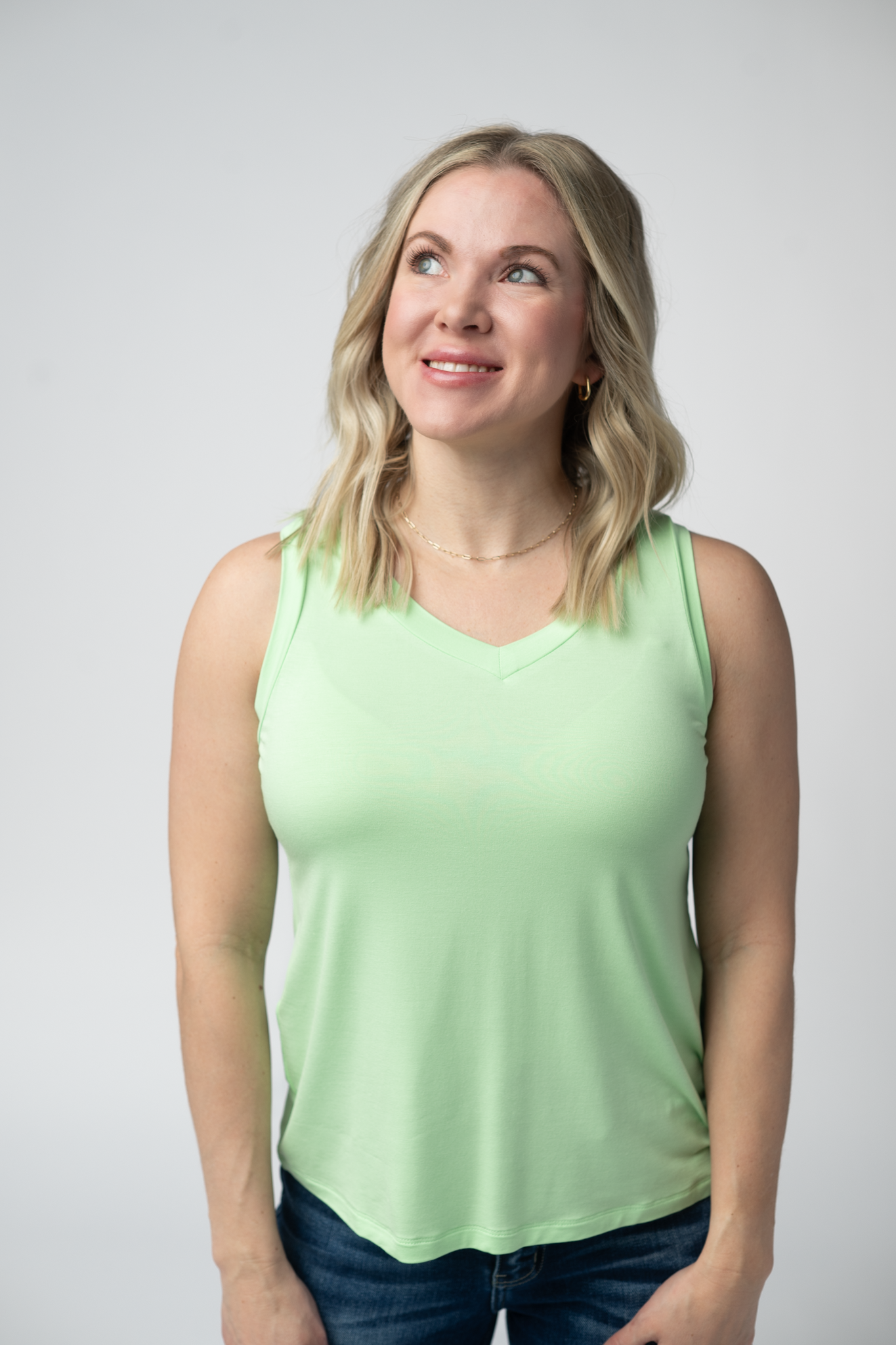 Woman wearing the Michelle Mae Noelle Tank in Lime, a lightweight v-neck sleeveless tank top in a bright lime green color