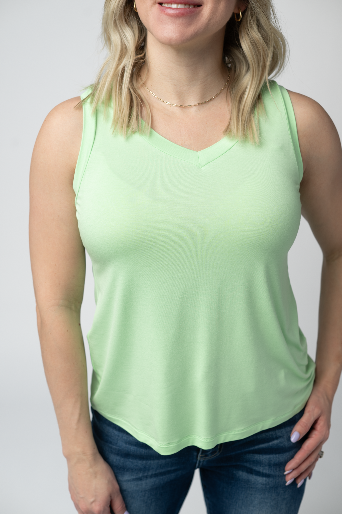 Woman wearing the Michelle Mae Noelle Tank in Lime, a lightweight v-neck sleeveless tank top in a bright lime green color