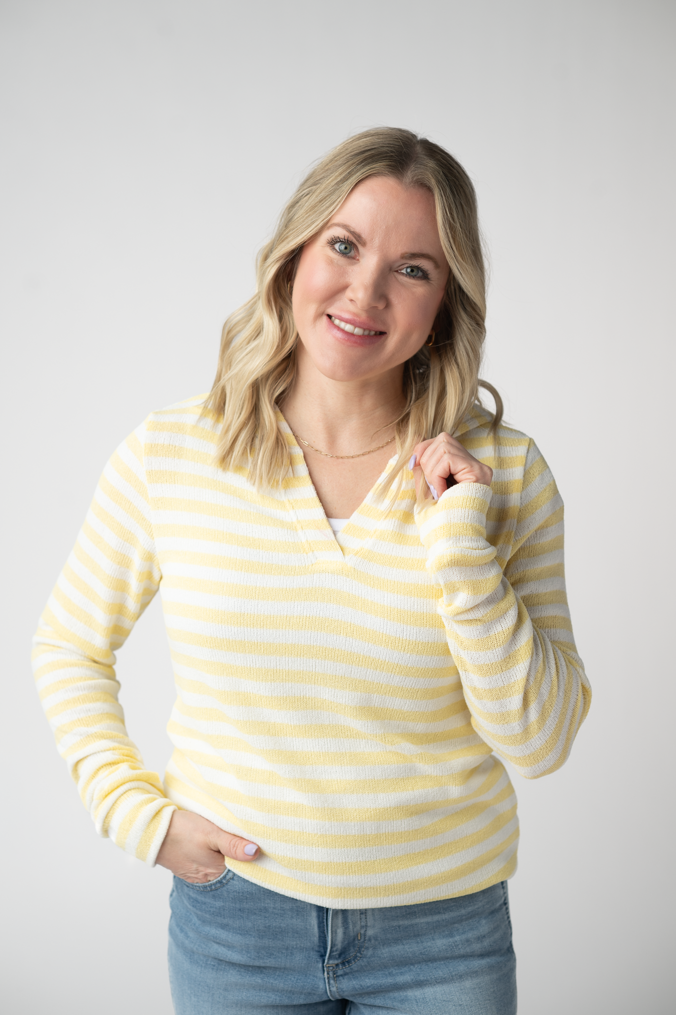 Woman wearing the Michelle Mae Amelia Striped Hoodie in Lemon, a lightweight yellow and white striped open-knit hoodie with cuffed sleeves and a V-neckline