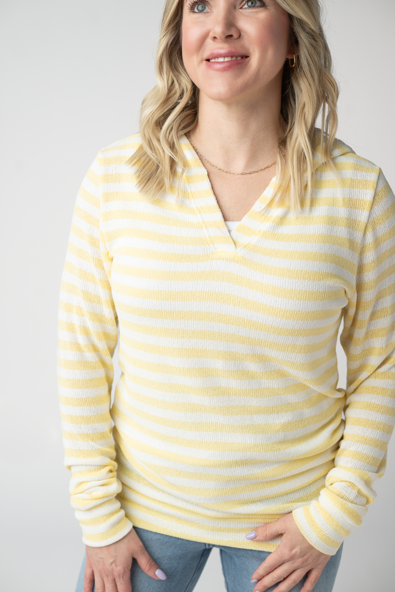 Woman wearing the Michelle Mae Amelia Striped Hoodie in Lemon, a lightweight yellow and white striped open-knit hoodie with cuffed sleeves and a V-neckline