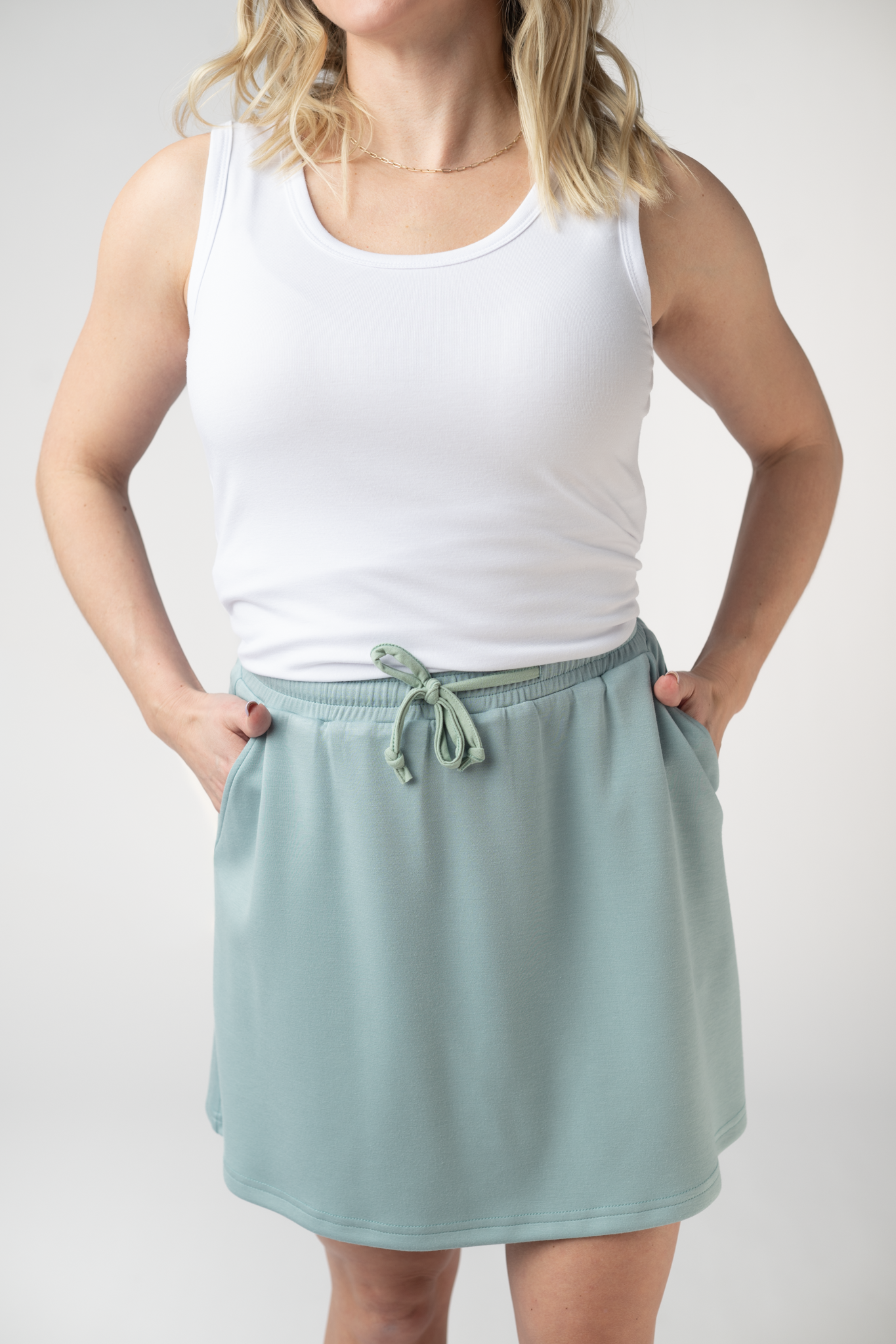 Woman wearing the Michelle Mae Serena Luxe Skort in Ocean Blue, a structured scuba skort with drawstring elastic waist and hidden pockets