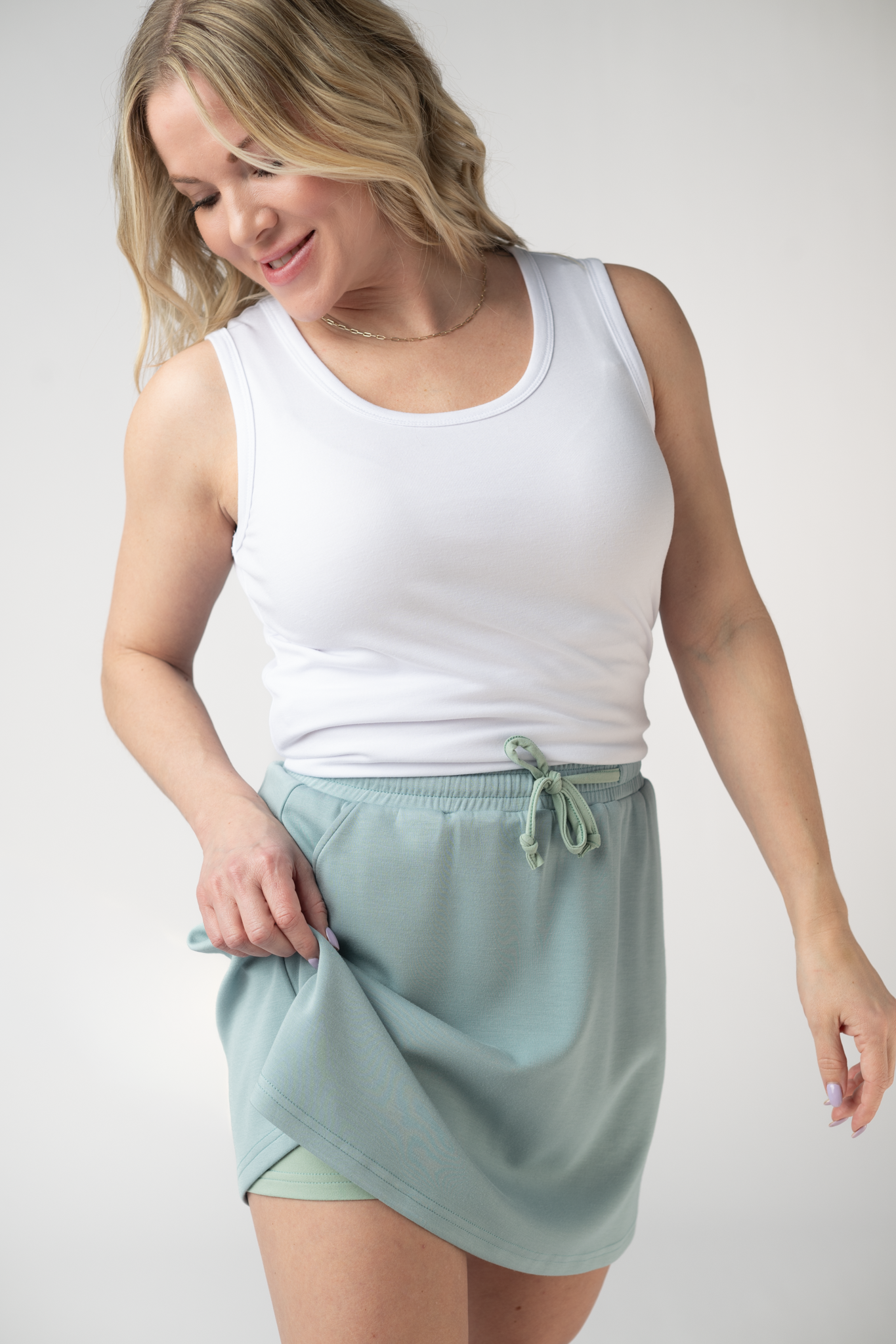 Woman wearing the Michelle Mae Serena Luxe Skort in Ocean Blue, a structured scuba skort with drawstring elastic waist and hidden pockets