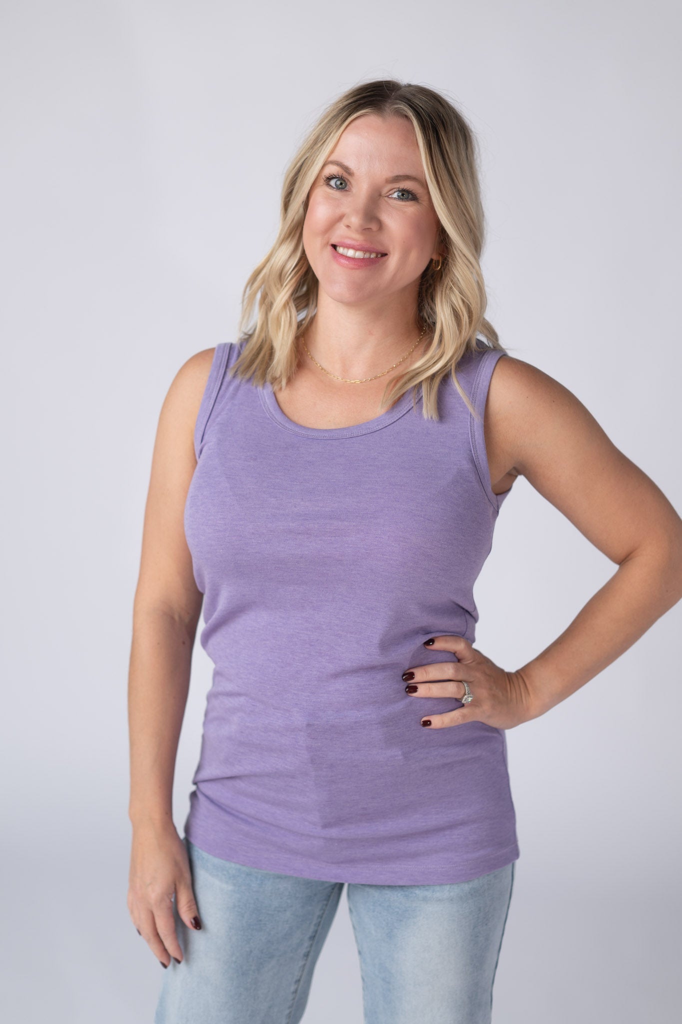 Woman wearing a heathered lavender Ava Tank with scoop neckline and micro ribbed fabric, paired with jeans