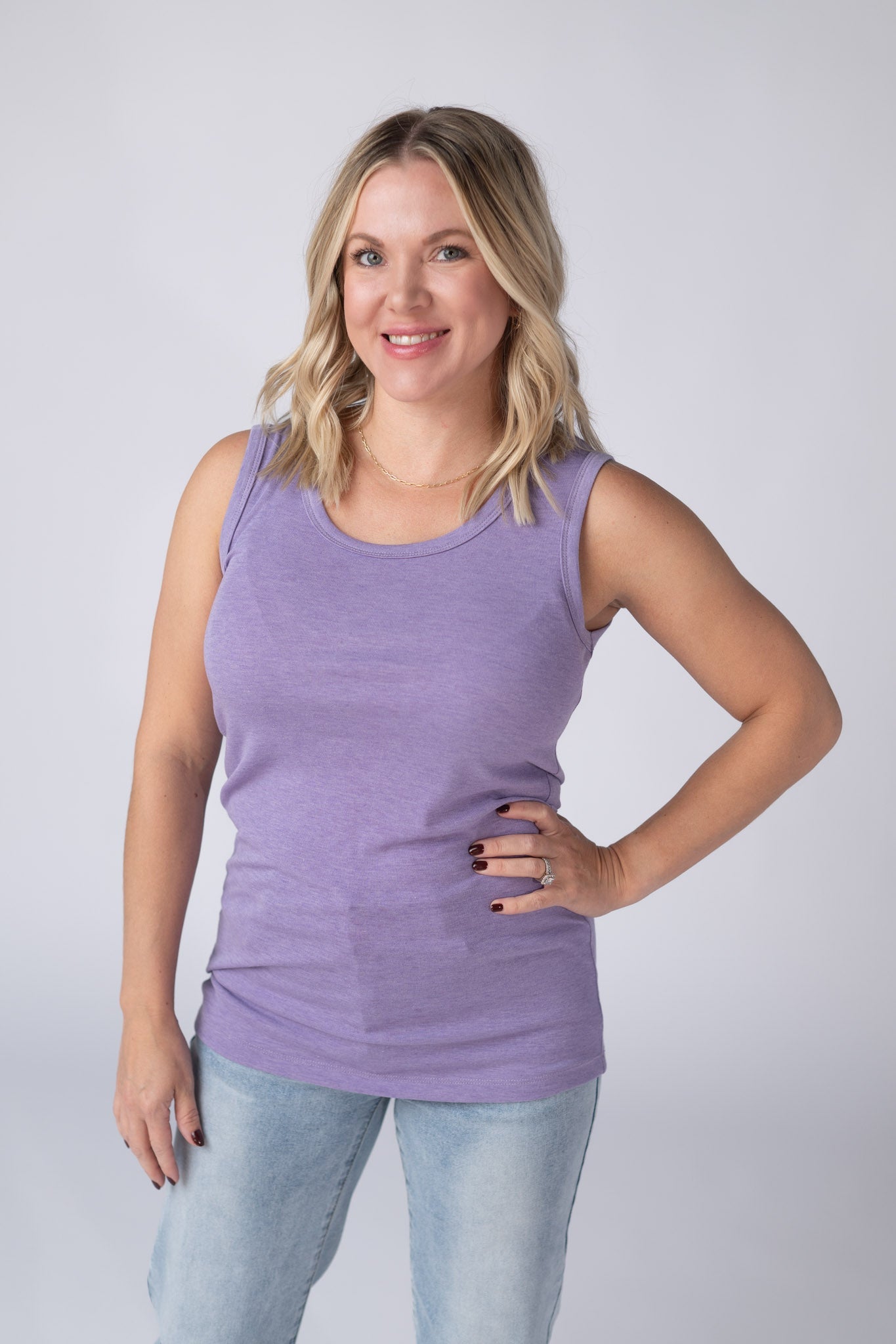 Woman wearing a heathered lavender Ava Tank with scoop neckline and micro ribbed fabric, paired with jeans