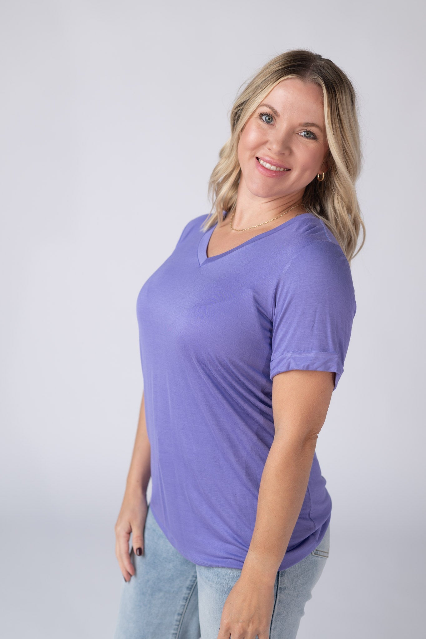 Woman wearing a periwinkle purple Sophie Tee with v-neckline and cuffed sleeves, paired with jeans