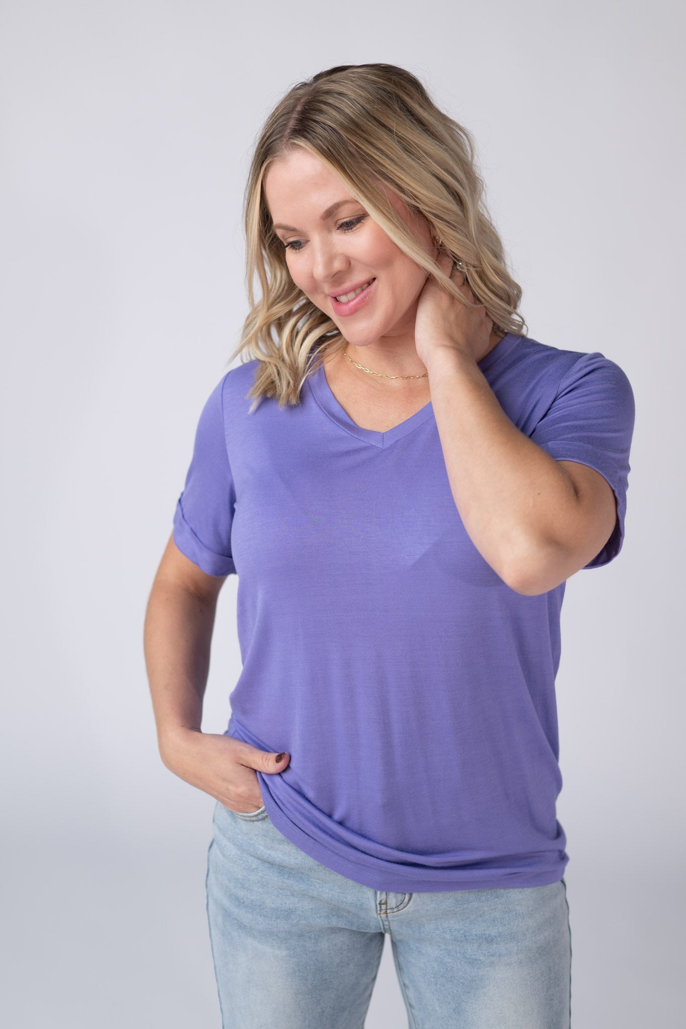Woman wearing a periwinkle purple Sophie Tee with v-neckline and cuffed sleeves, paired with jeans