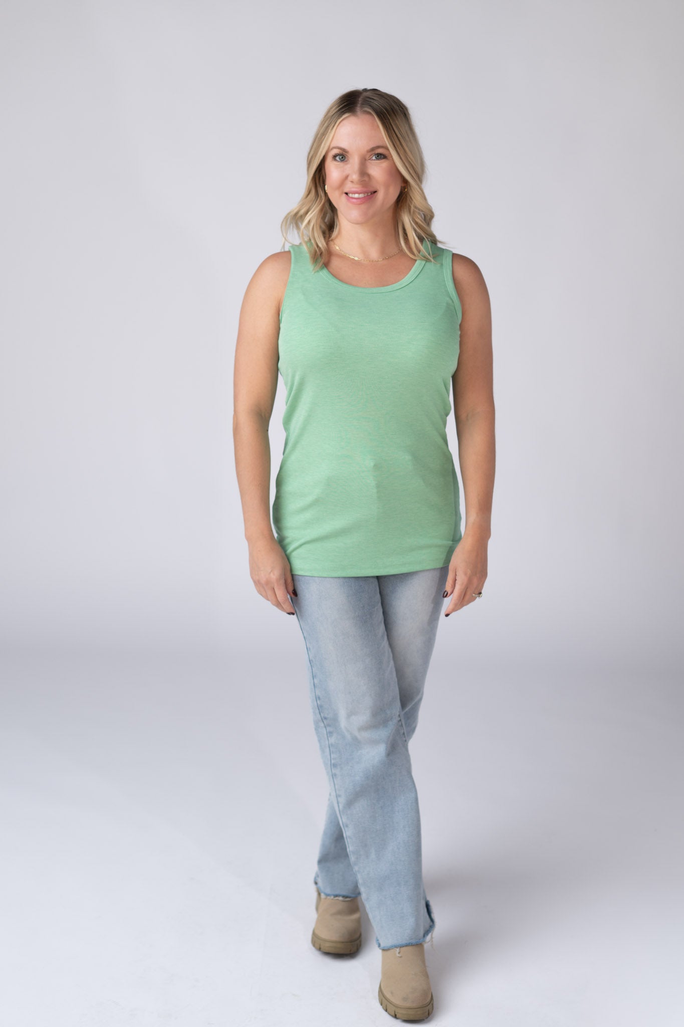 Woman wearing a mint green Ava Tank with scoop neckline and micro ribbed fabric, paired with jeans