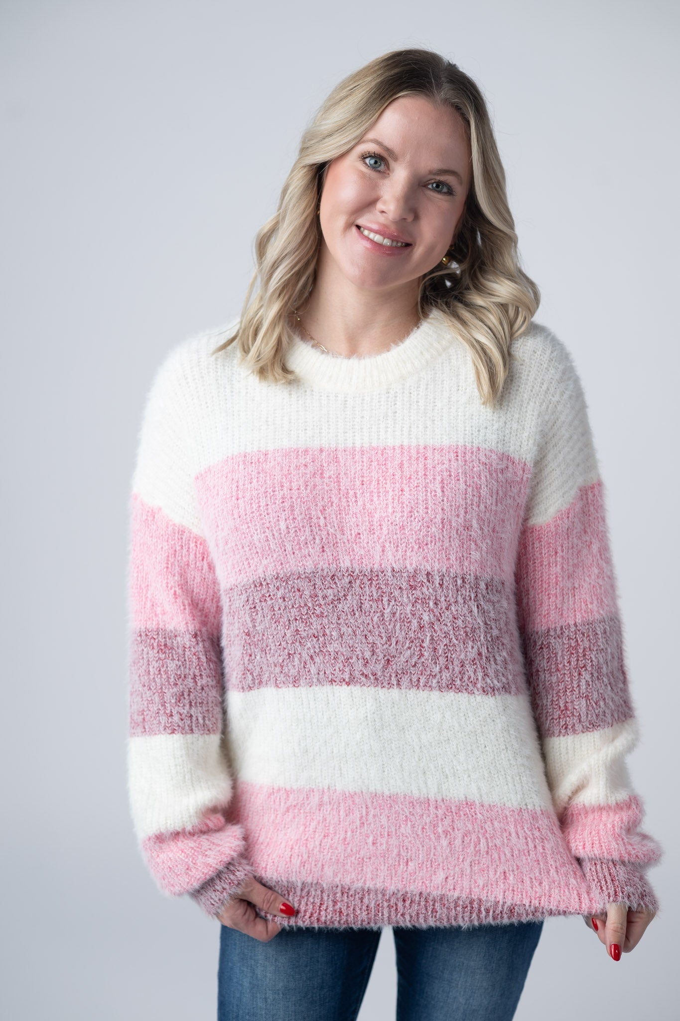 Woman wearing ultra-soft fuzzy colorblock sweater with ivory, pink, and mauve stripes and crew neckline