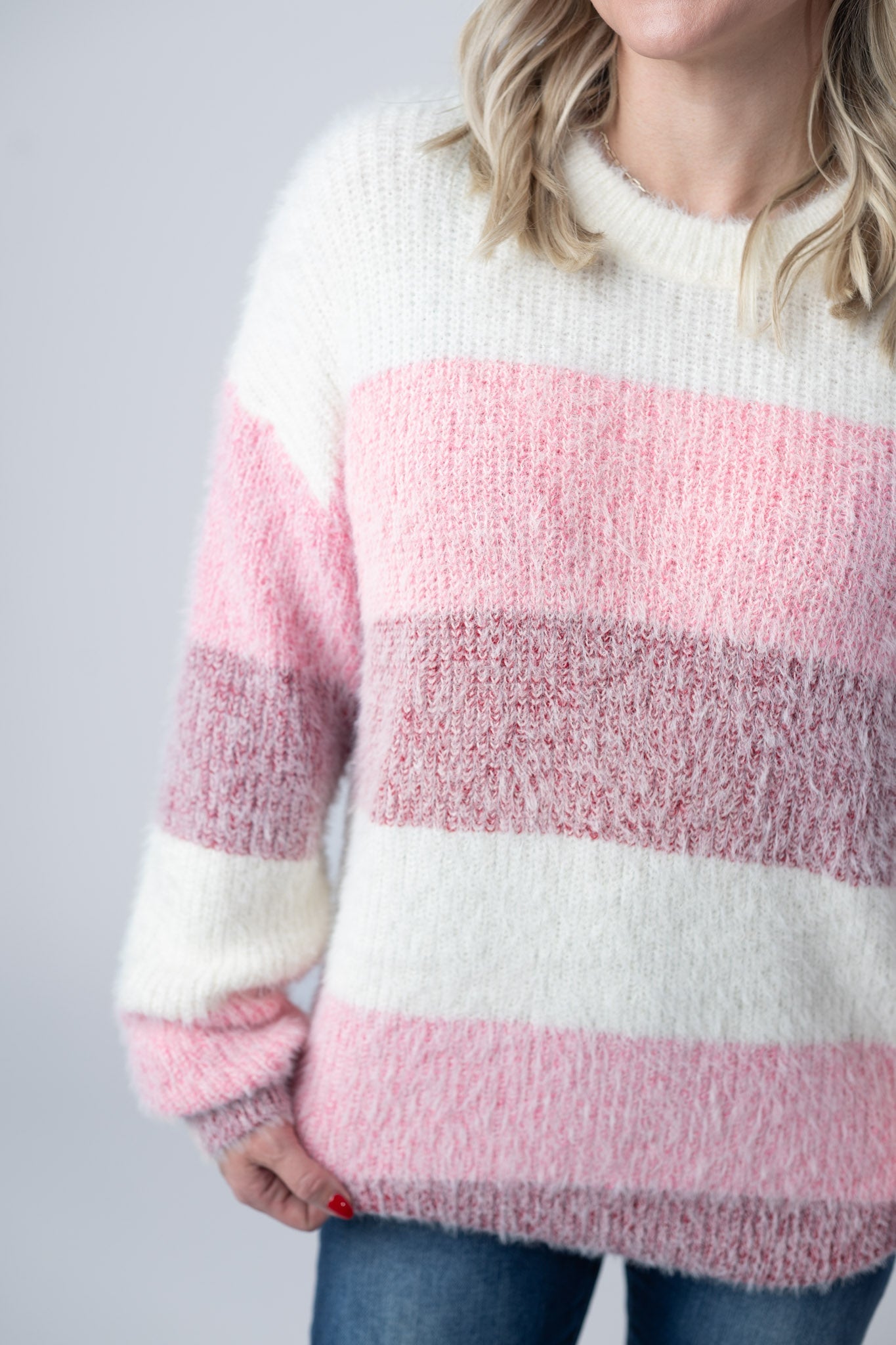 Woman wearing ultra-soft fuzzy colorblock sweater with ivory, pink, and mauve stripes and crew neckline
