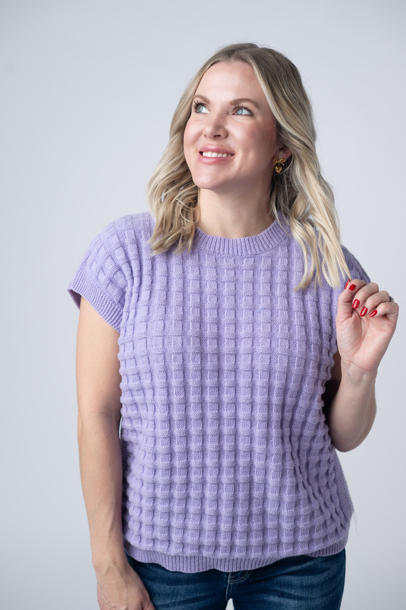 Woman wearing lavender short sleeve sweater top with textured waffle knit pattern and crew neckline