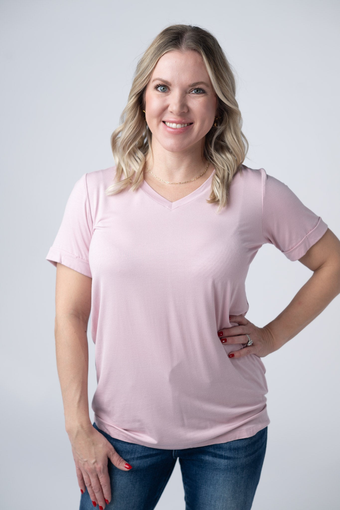 Woman wearing soft pink v-neck tee with cuffed sleeves and jeans