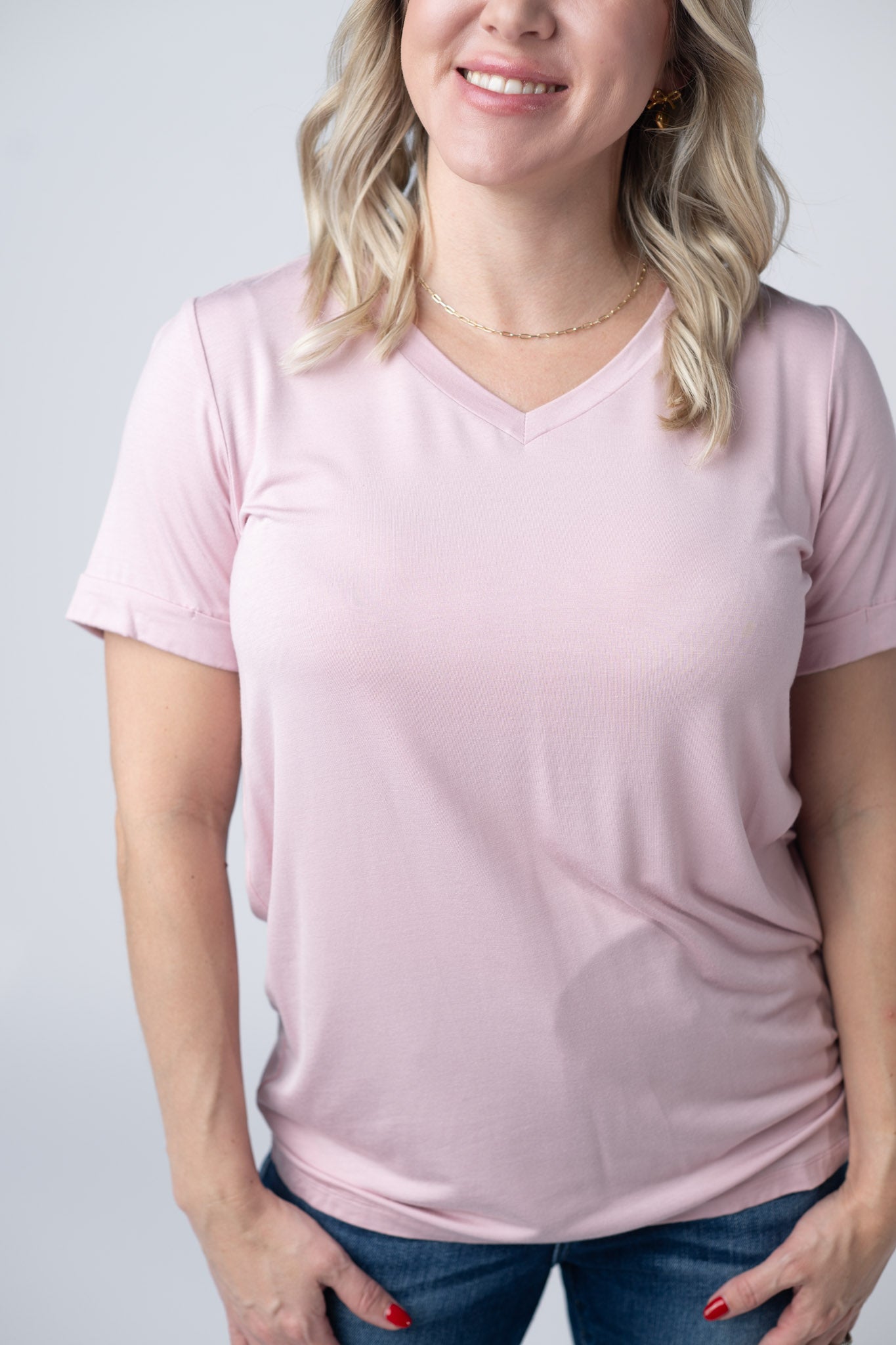 Woman wearing soft pink v-neck tee with cuffed sleeves and jeans
