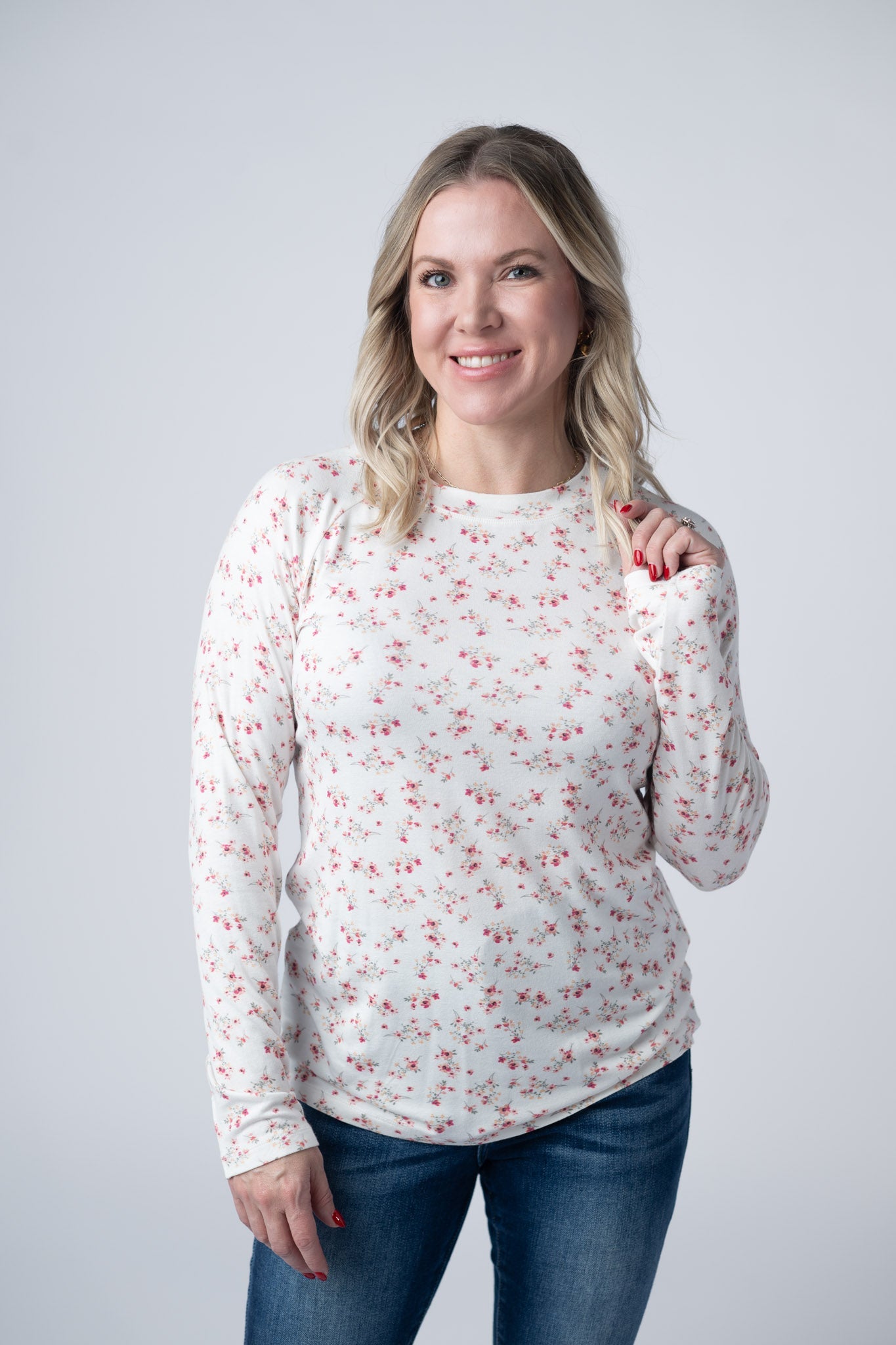 Woman wearing white fitted long sleeve top with small pink floral print and high neckline