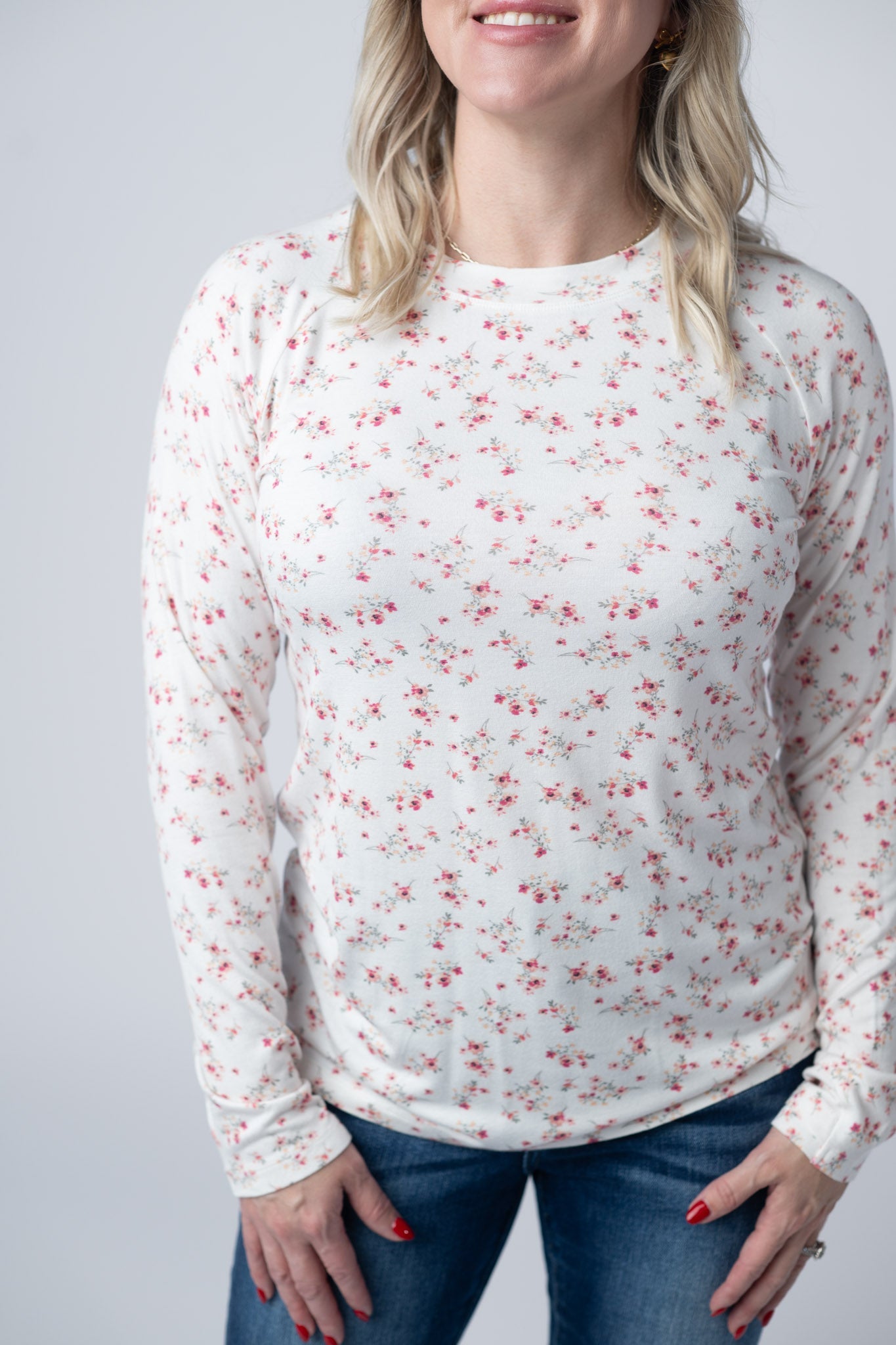 Woman wearing white fitted long sleeve top with small pink floral print and high neckline