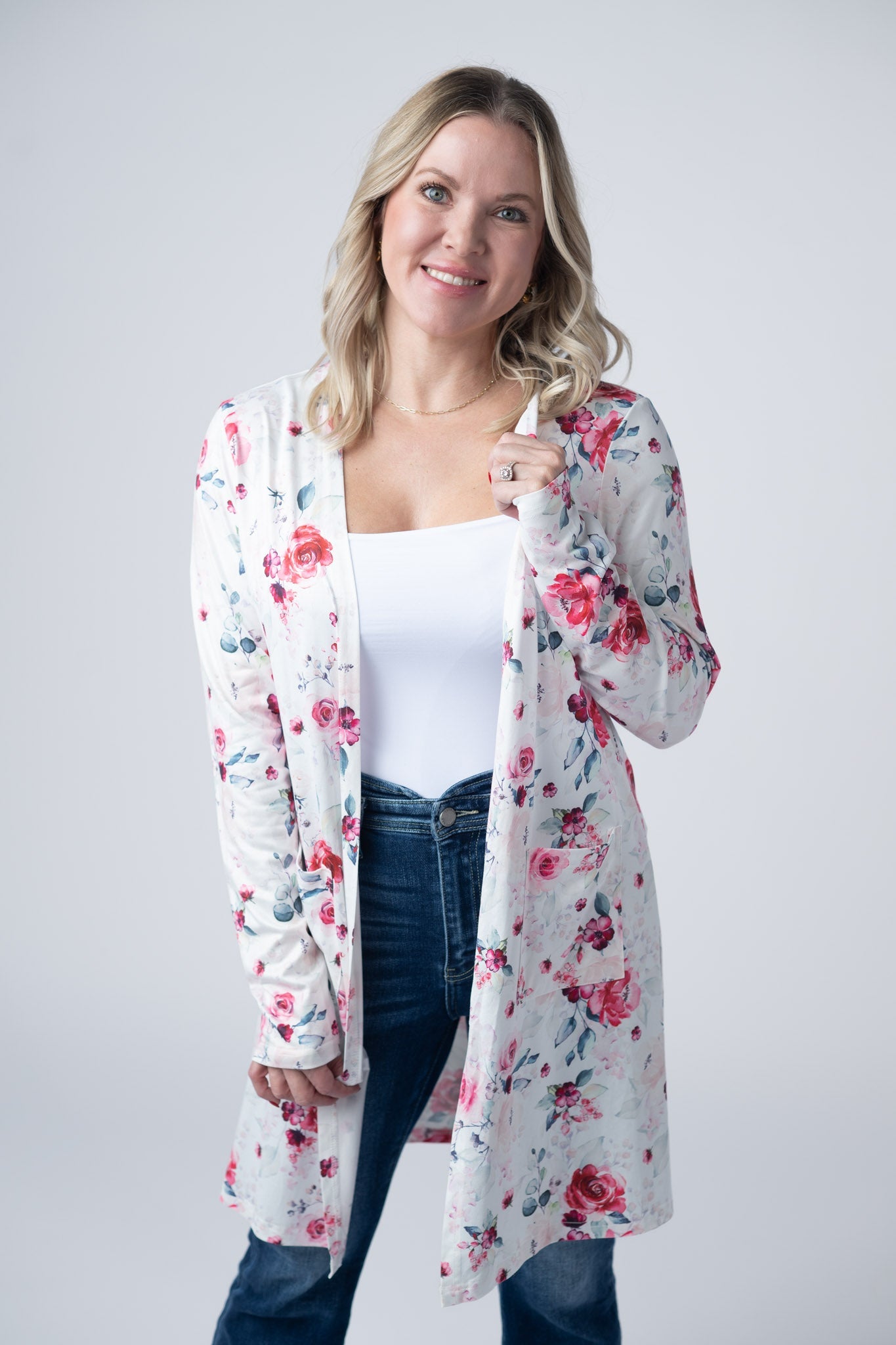 Woman wearing white lightweight open front cardigan with pink floral print and side pockets