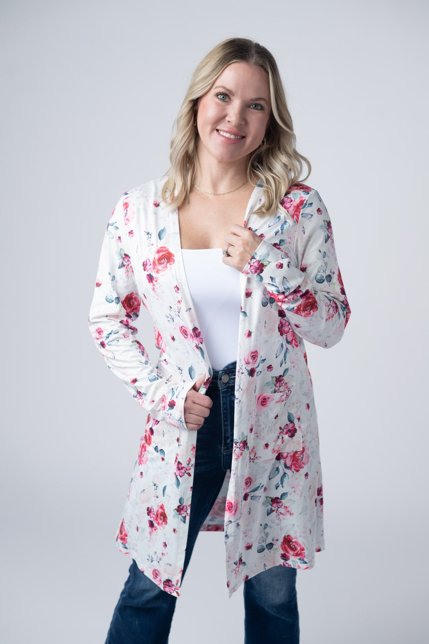 Woman wearing white lightweight open front cardigan with pink floral print and side pockets