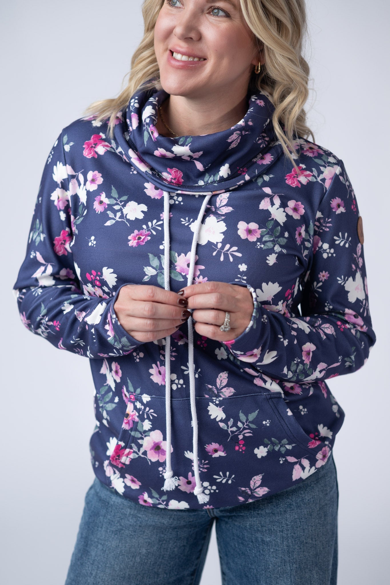 Women's funnel neck sweatshirt in navy blue with pink and white floral print featuring cowl neck with drawstrings and kangaroo pocket