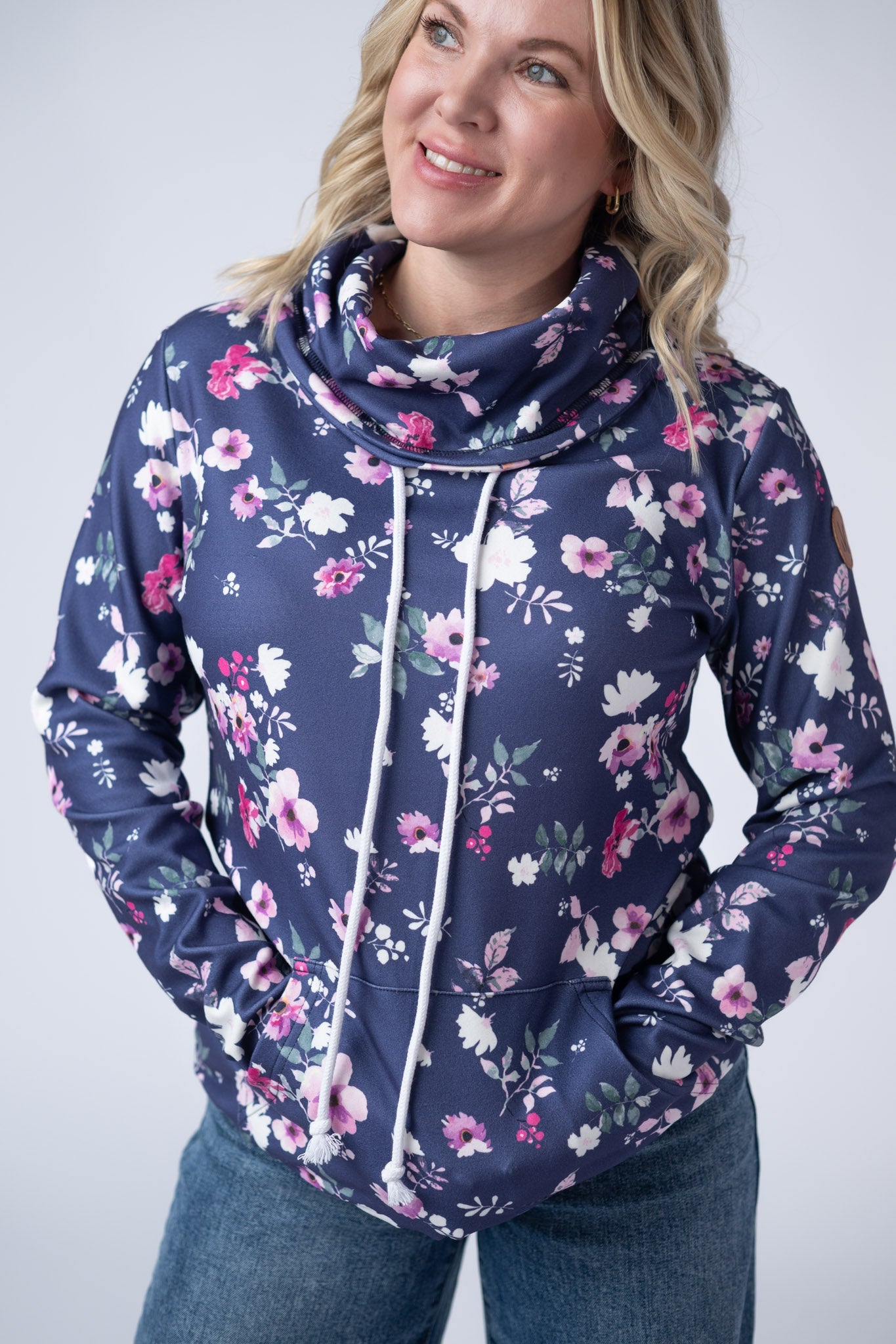 Women's funnel neck sweatshirt in navy blue with pink and white floral print featuring cowl neck with drawstrings and kangaroo pocket
