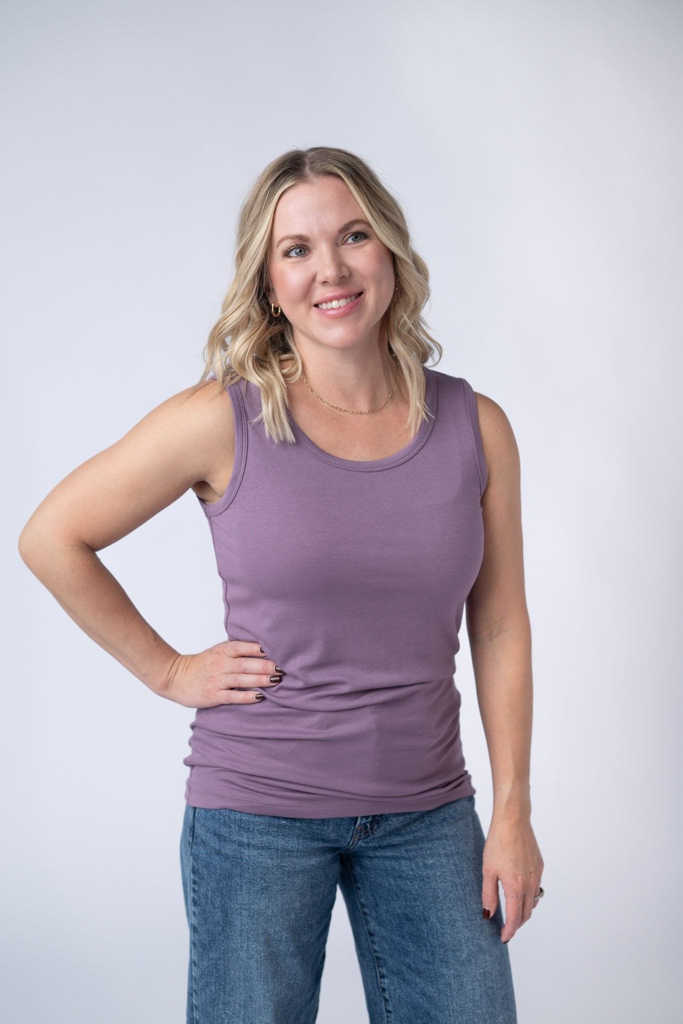 Woman wearing a dusty lavender Ava Tank with scoop neckline and micro ribbed fabric, paired with jeans