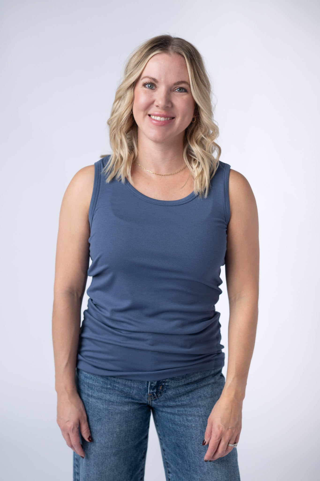 Woman wearing a dusty blue Ava Tank with scoop neckline and micro ribbed fabric, paired with jeans