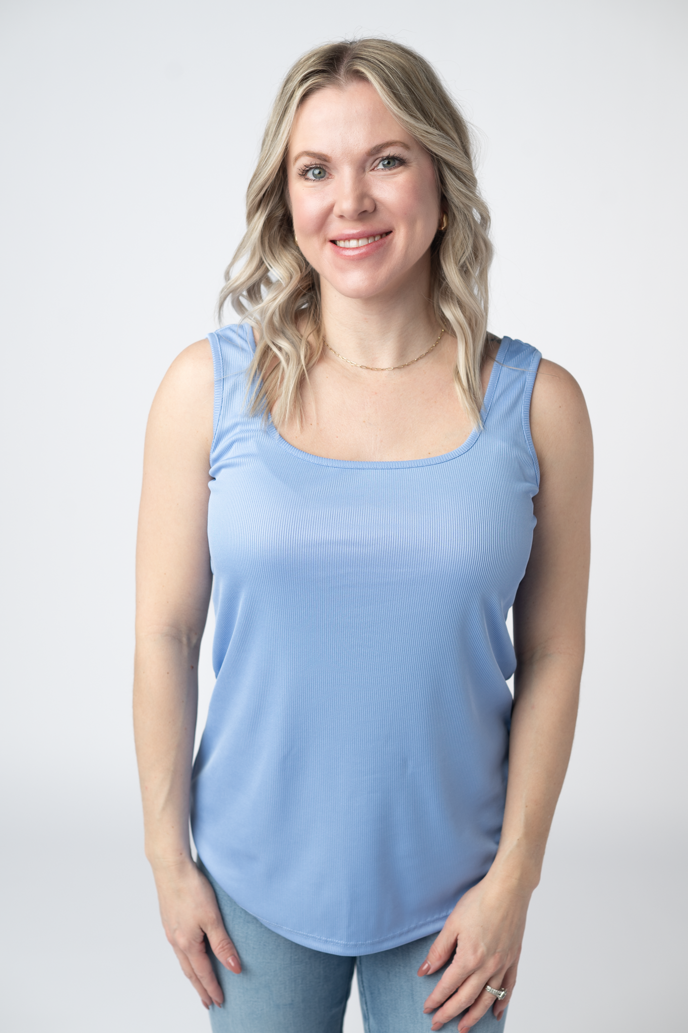  Woman wearing a sky blue Rachel Ribbed Tank with scoop neck and curved hem in lightweight ribbed fabric