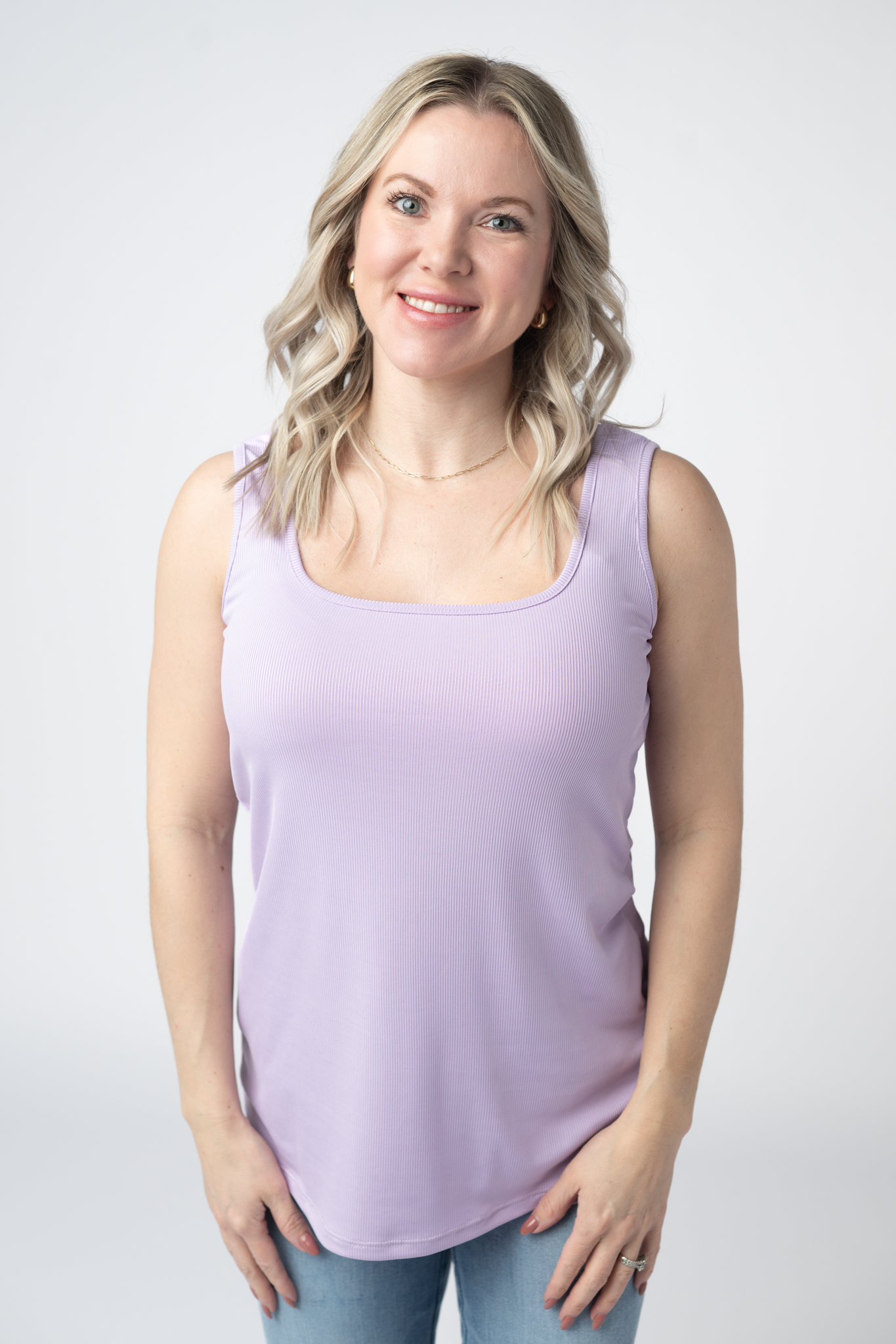 Woman wearing a lavender Rachel Ribbed Tank with scoop neck and curved hem in lightweight ribbed fabric