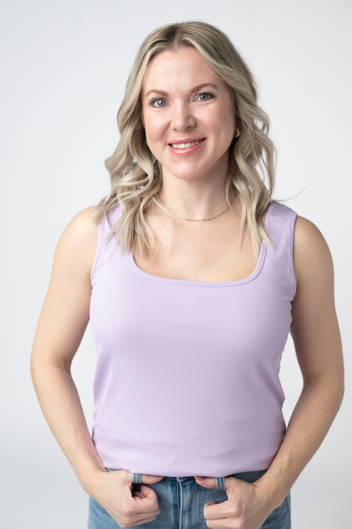 Woman wearing a lavender Rachel Ribbed Tank with scoop neck and curved hem in lightweight ribbed fabric