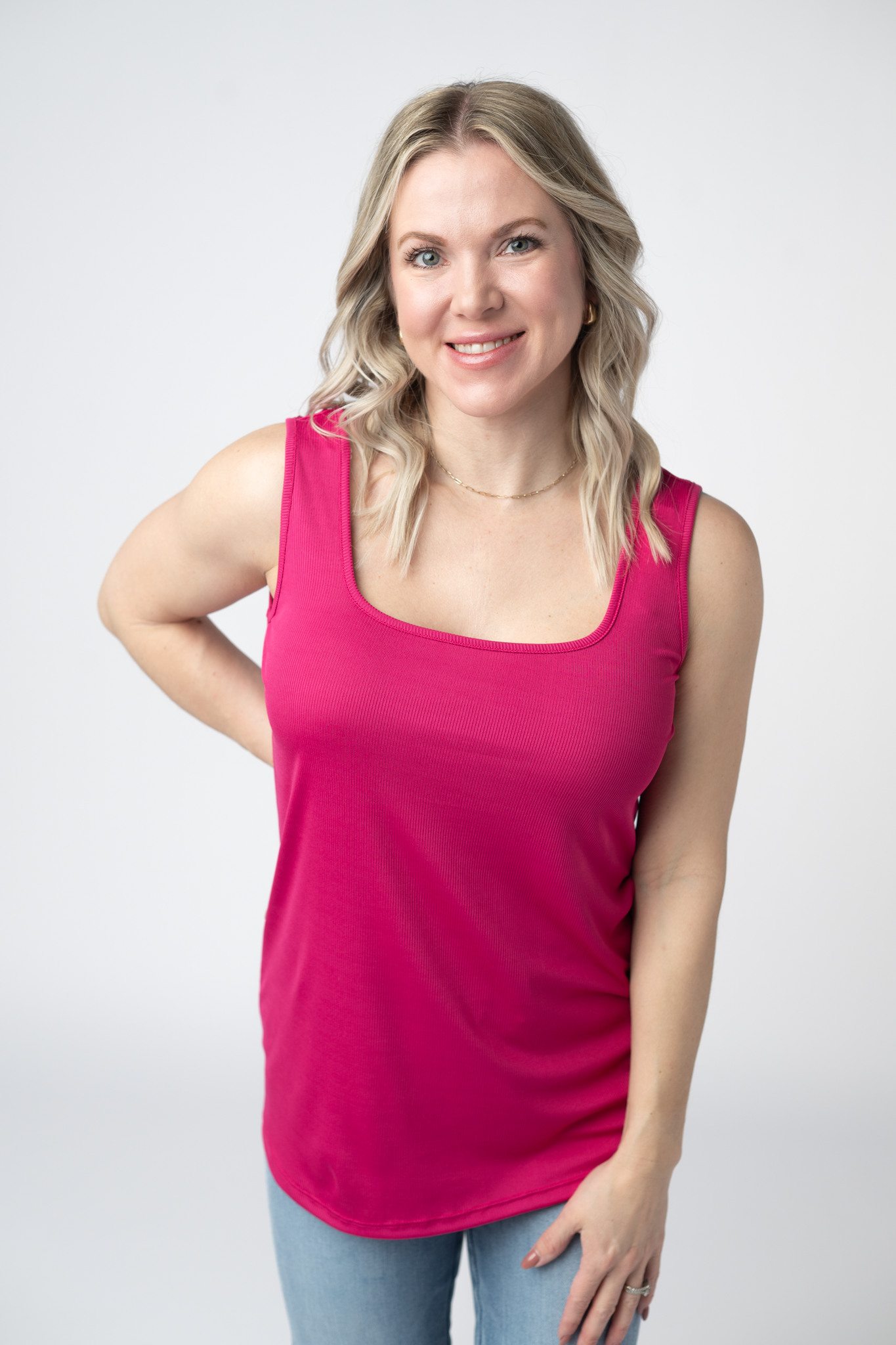 Woman wearing a hot pink Rachel Ribbed Tank with scoop neck and curved hem in lightweight ribbed fabric