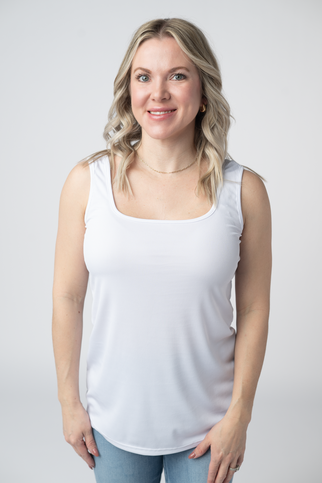 Woman wearing a white Rachel Ribbed Tank with scoop neck and curved hem in lightweight ribbed fabric