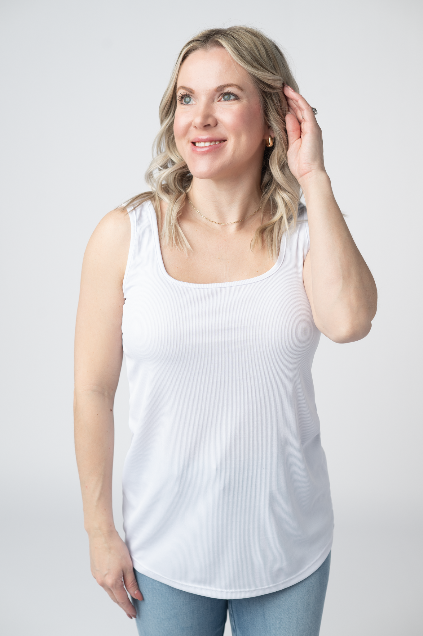 Woman wearing a white Rachel Ribbed Tank with scoop neck and curved hem in lightweight ribbed fabric