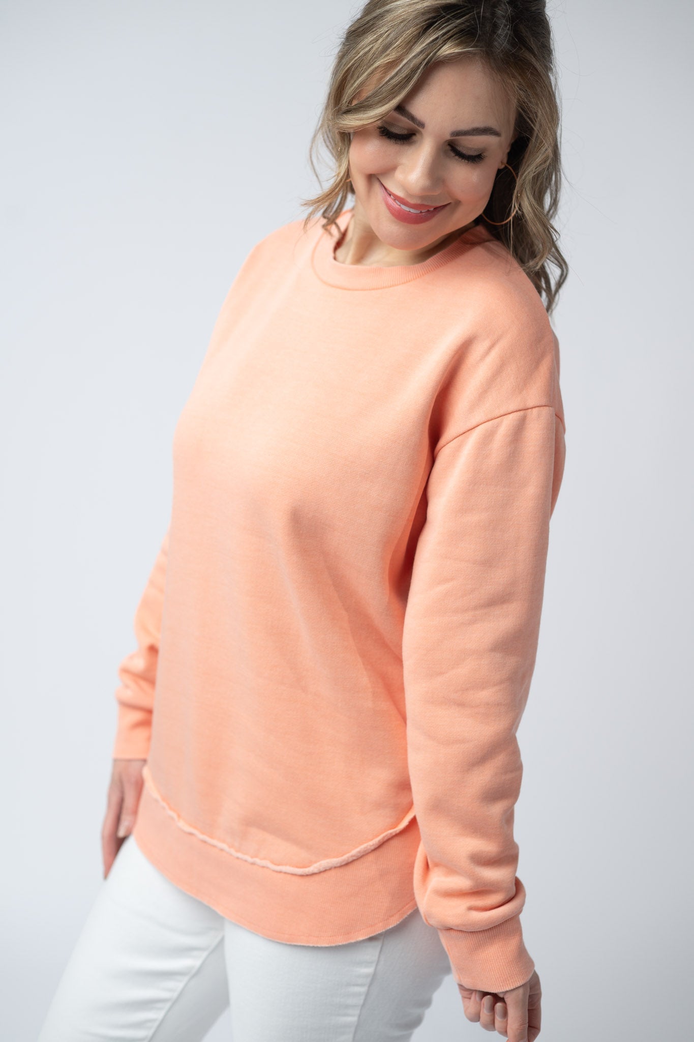 Women's vintage wash pullover in Spring Peach with crew neck, relaxed fit, and raw edge hem details, paired with matching drawstring shorts
